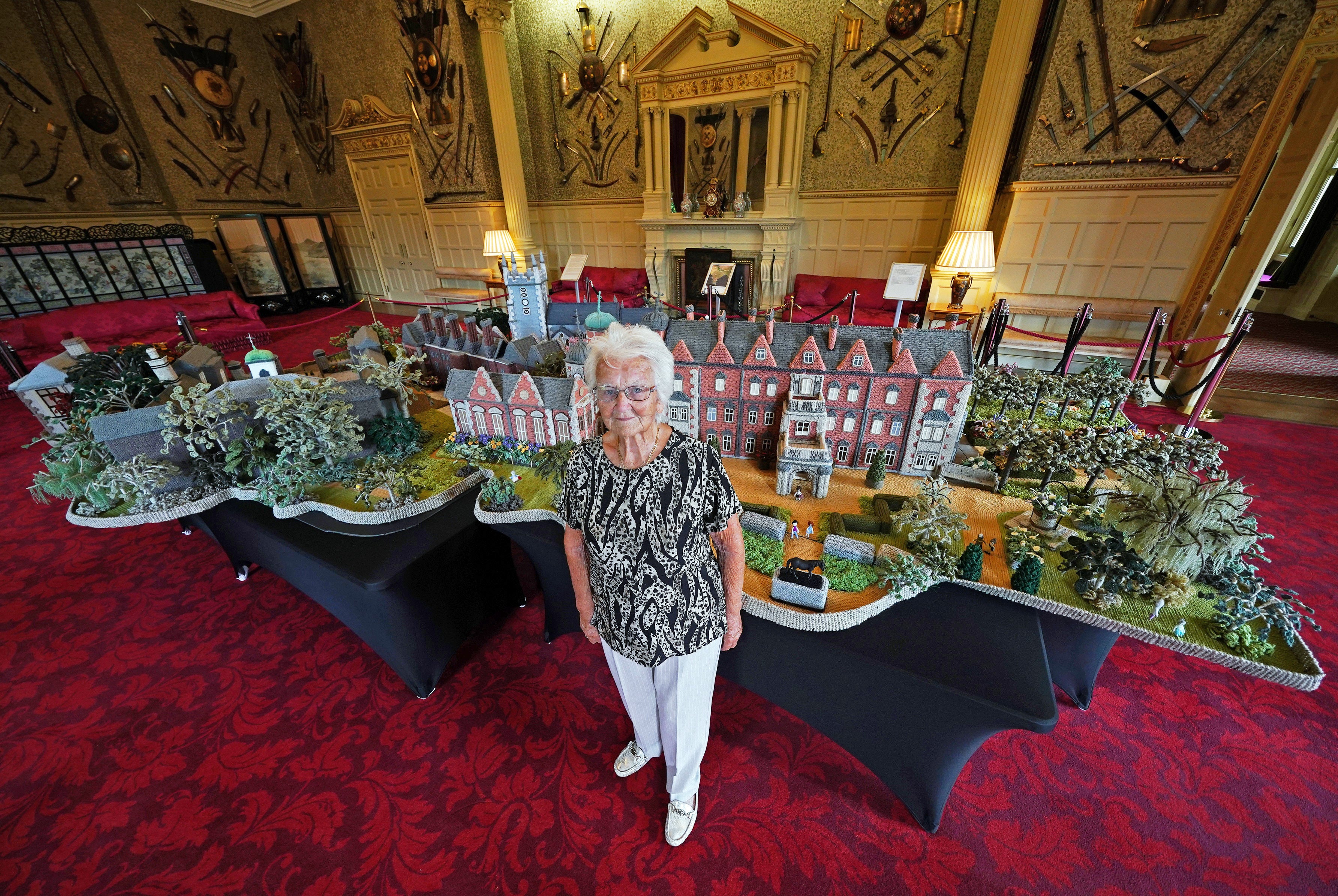 Ninety-two-year-old Margaret Seaman from Great Yarmouth, Norfolk, stands next to her creation ‘Knitted Sandringham’, on display in the Ballroom of Sandringham House last year (Yui Mok/PA)