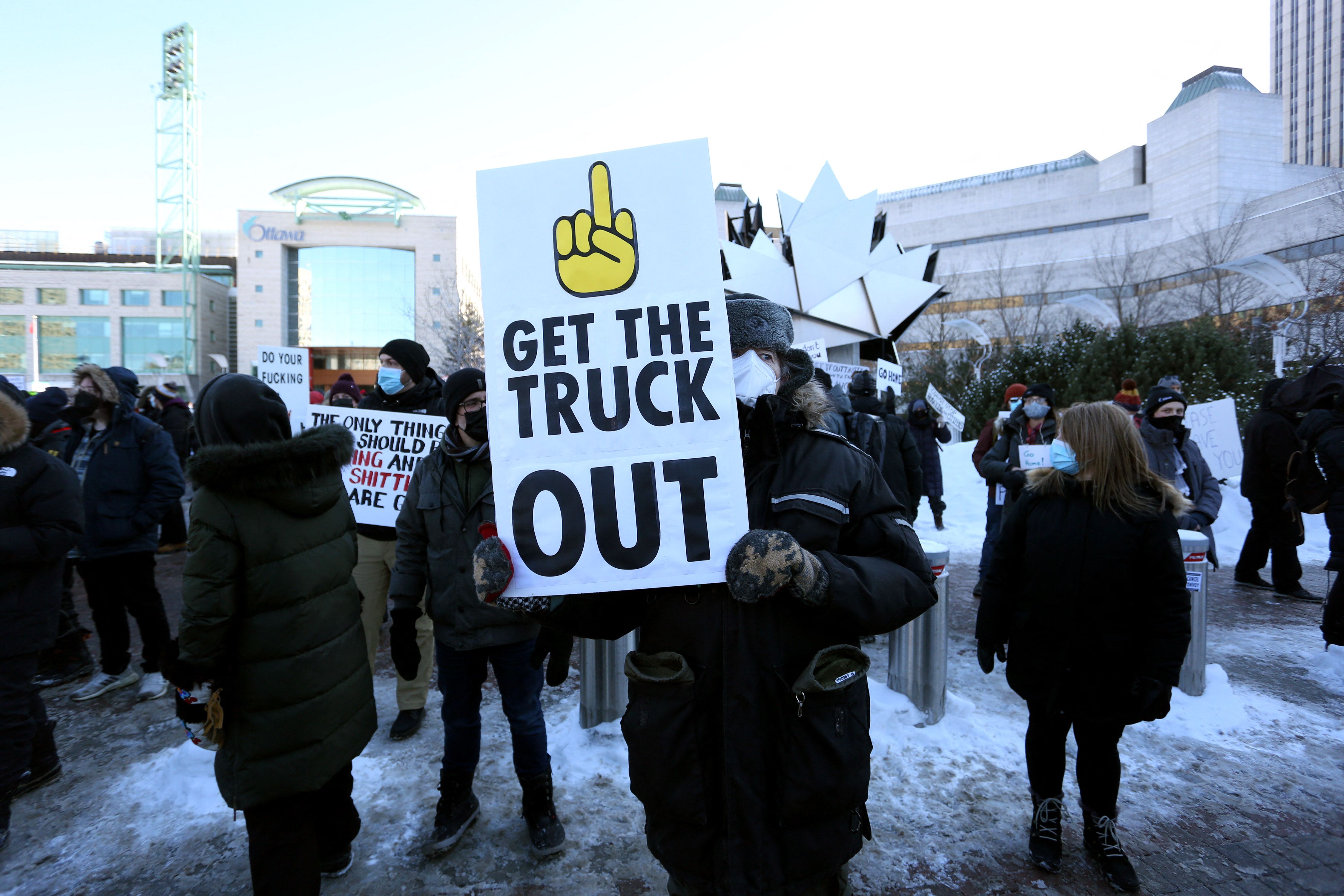 A counter-protester in Ottawa holds a sign opposing the truckers demonstrating against Covid-19 vaccine mandates