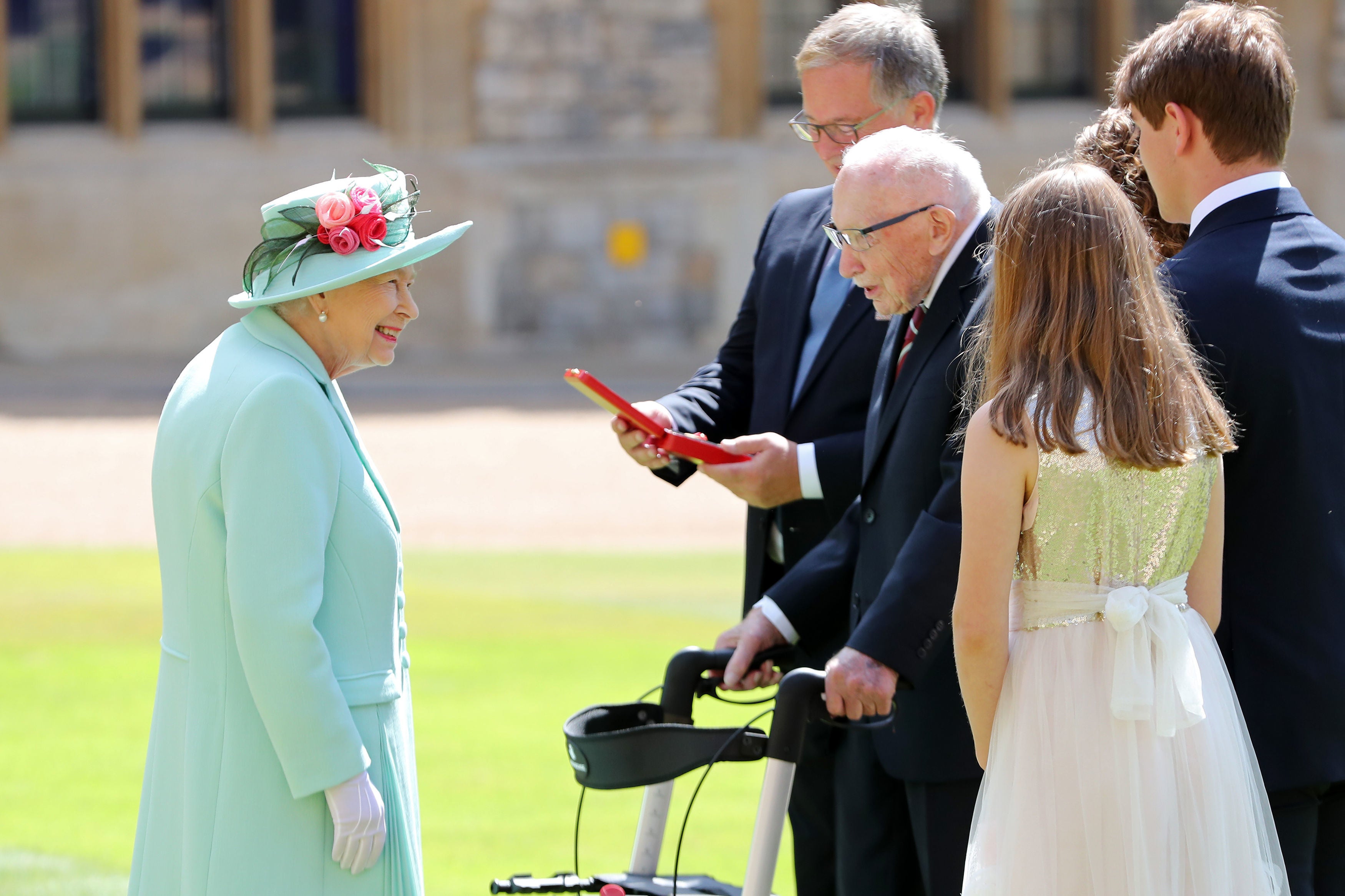 Queen Elizabeth II talking Captain Sir Thomas Moore and his family after awarding his knighthood during a ceremony at Windsor Castle.