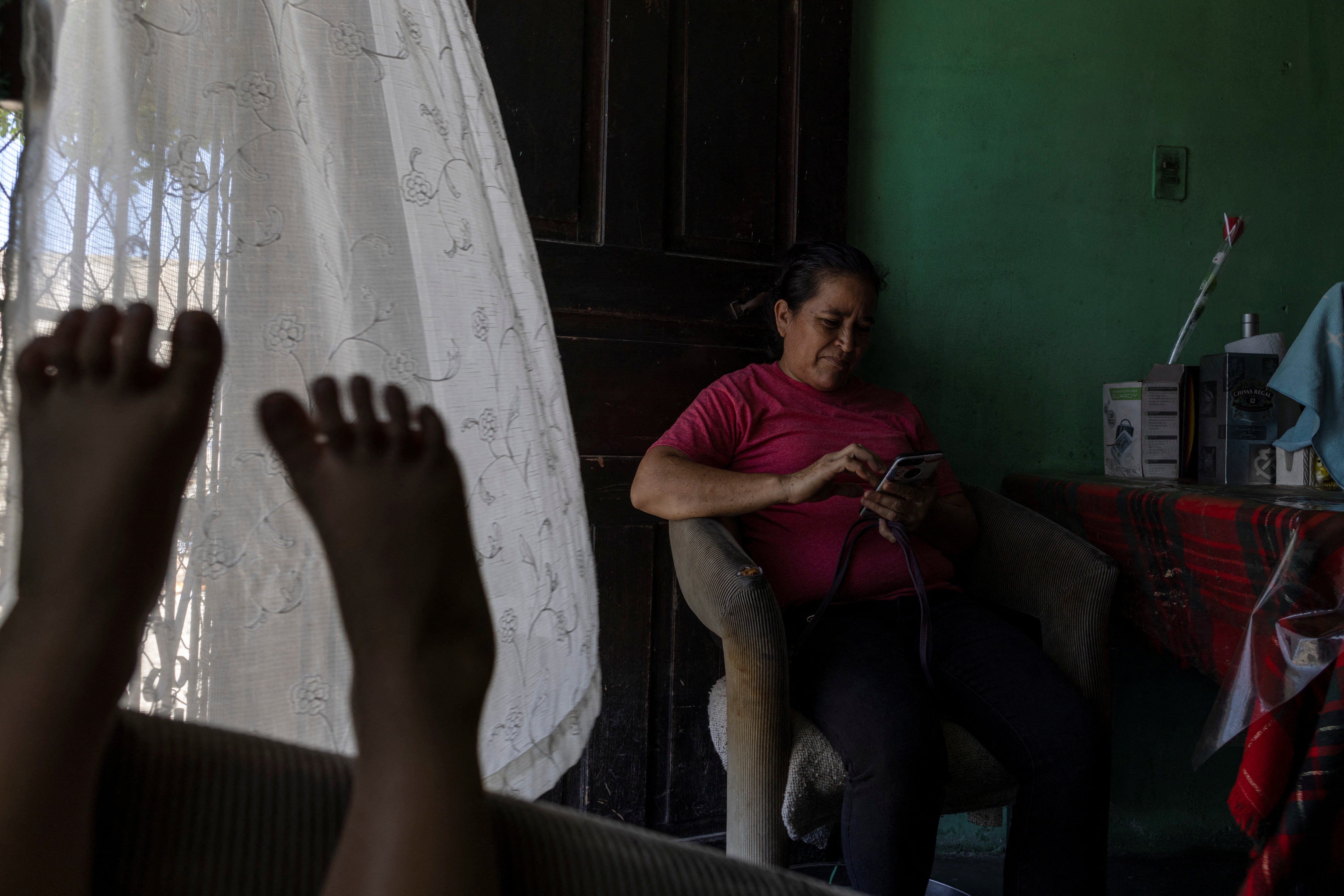 Maria checks her phone while waiting in Honduras