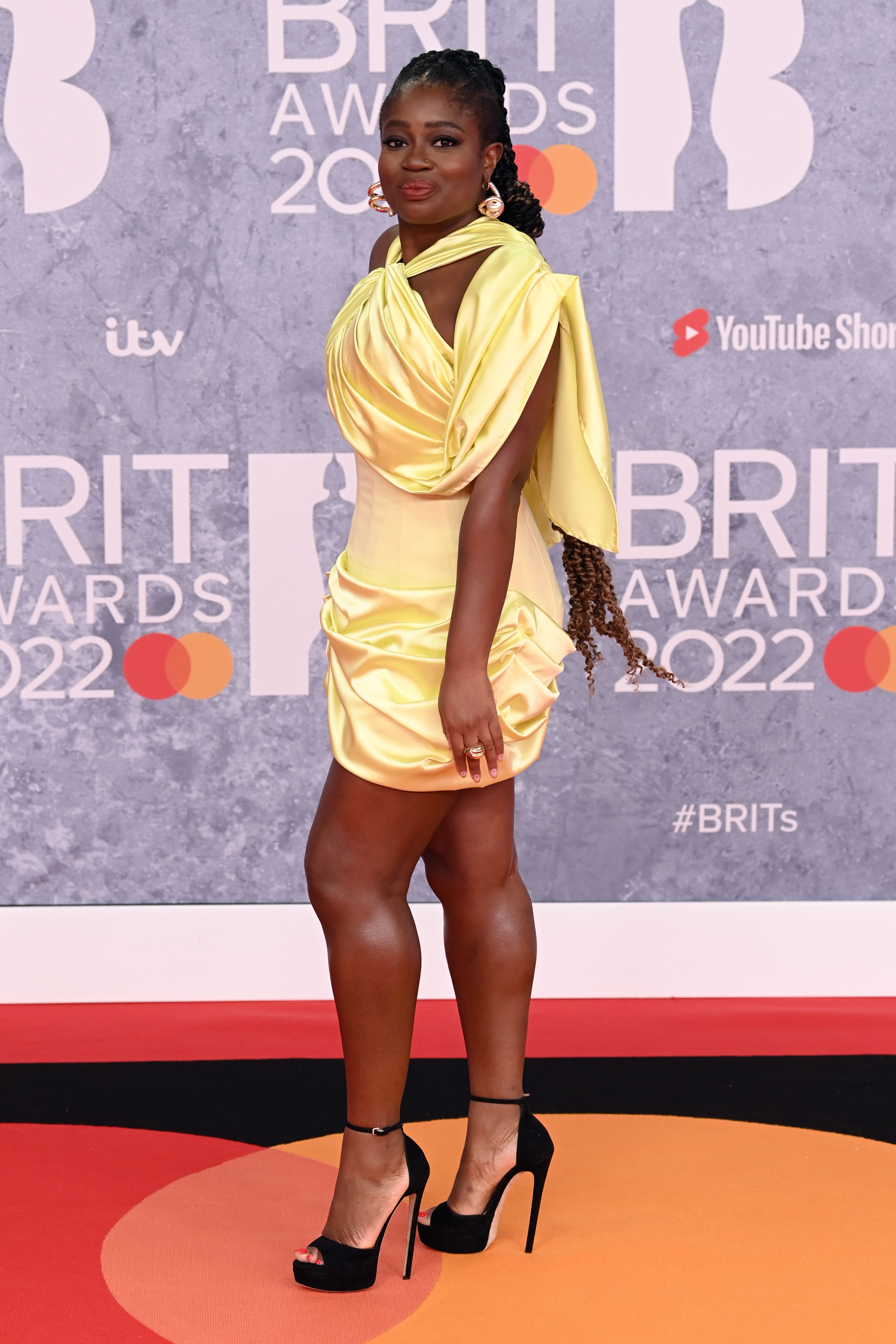The radio host wore a satin yellow mini dress that featured a ruched skirt and a halter-neck on the red carpet, pairing the look with black platform stilettos from Jimmy Choo.