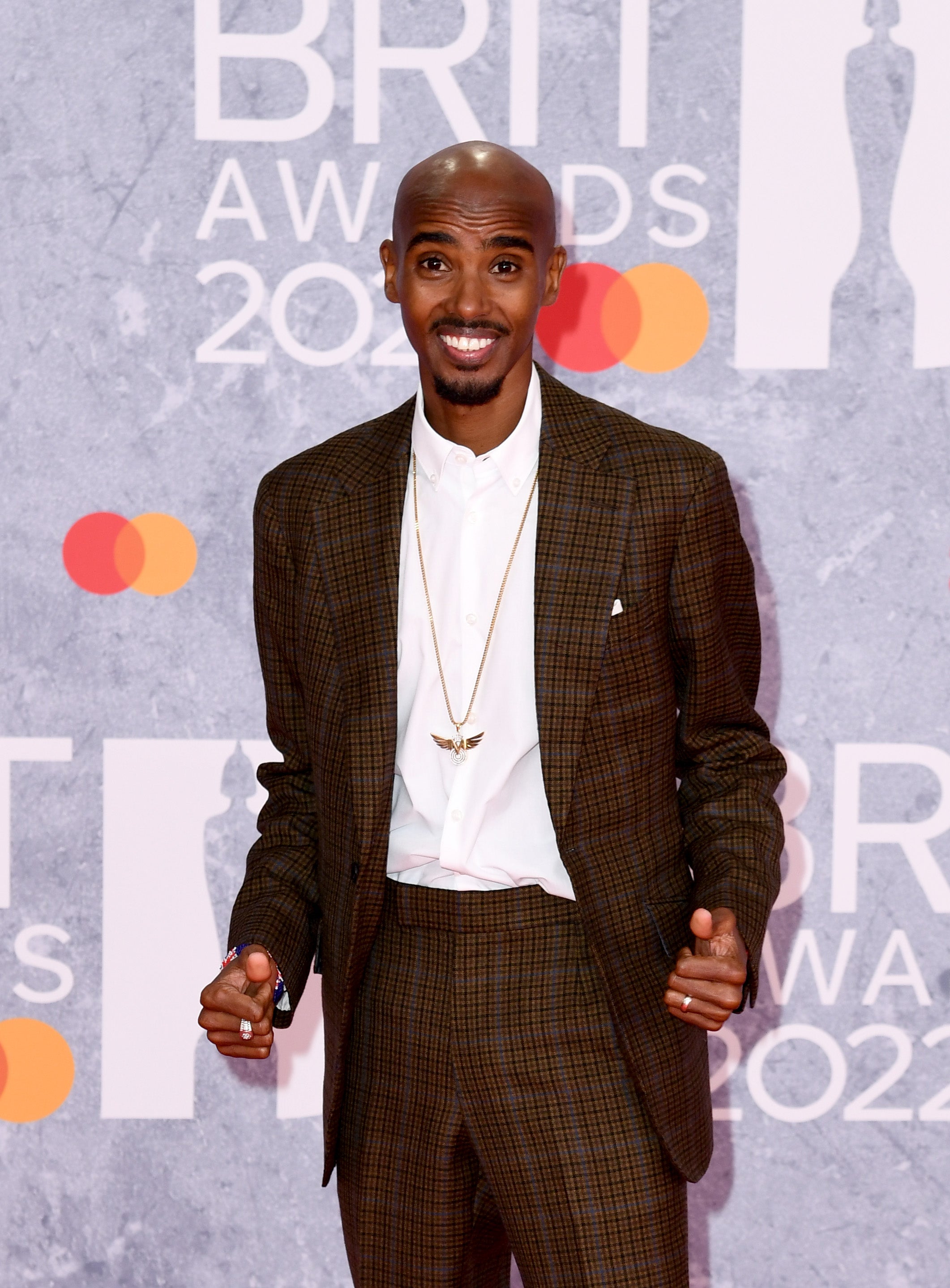 The Olympic champion arrived at the ceremony wearing a brown checked suit over the top of a white shirt. Farah paired the look with Nike trainers.