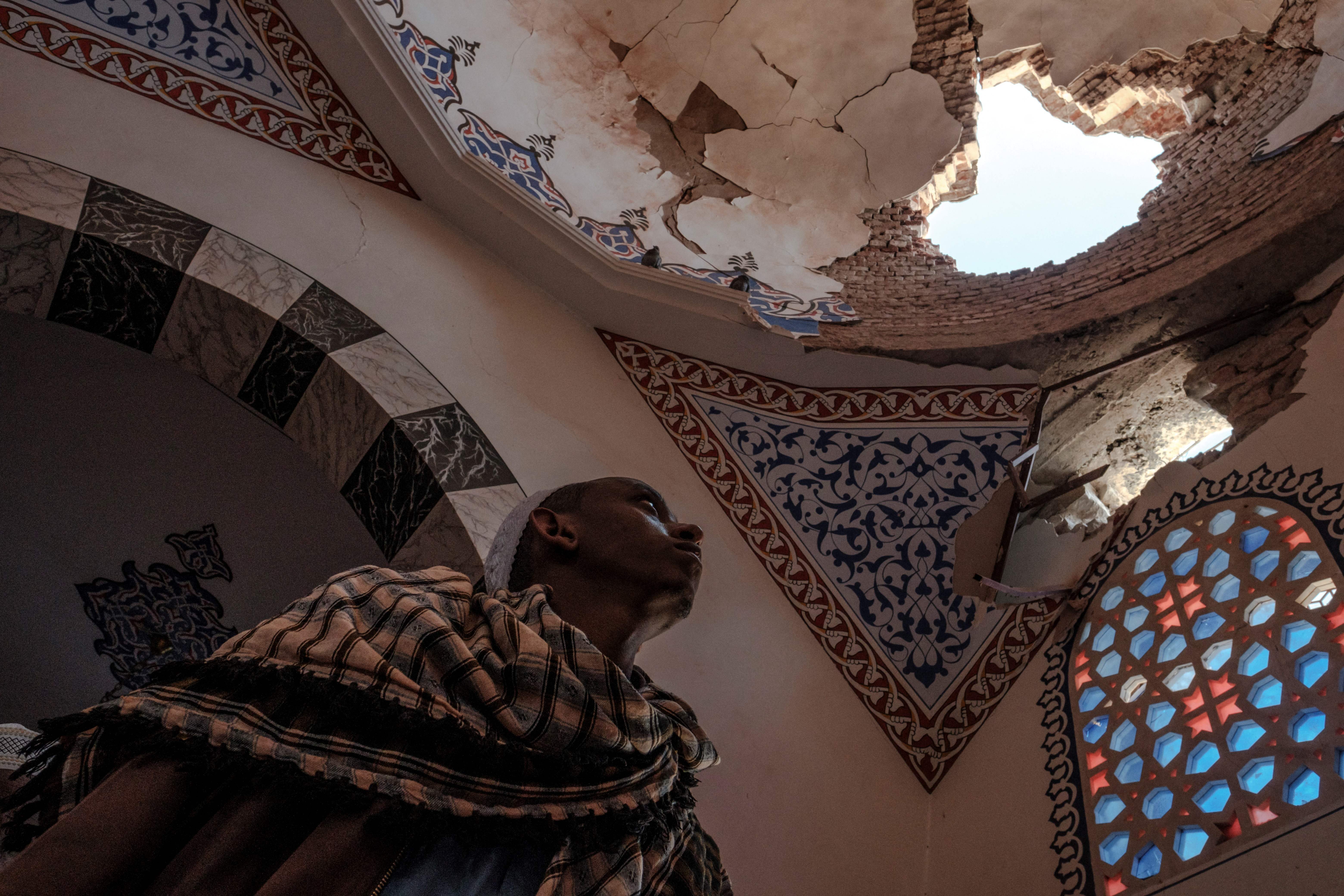 <p>An Ethiopian Muslim stands inside a damaged mausoleum at the al-Nejashi Mosque, one of the oldest in Africa and allegedly damaged by Eritrean forces shelling, in Negash, north of Wukro, 1 March 2021</p>