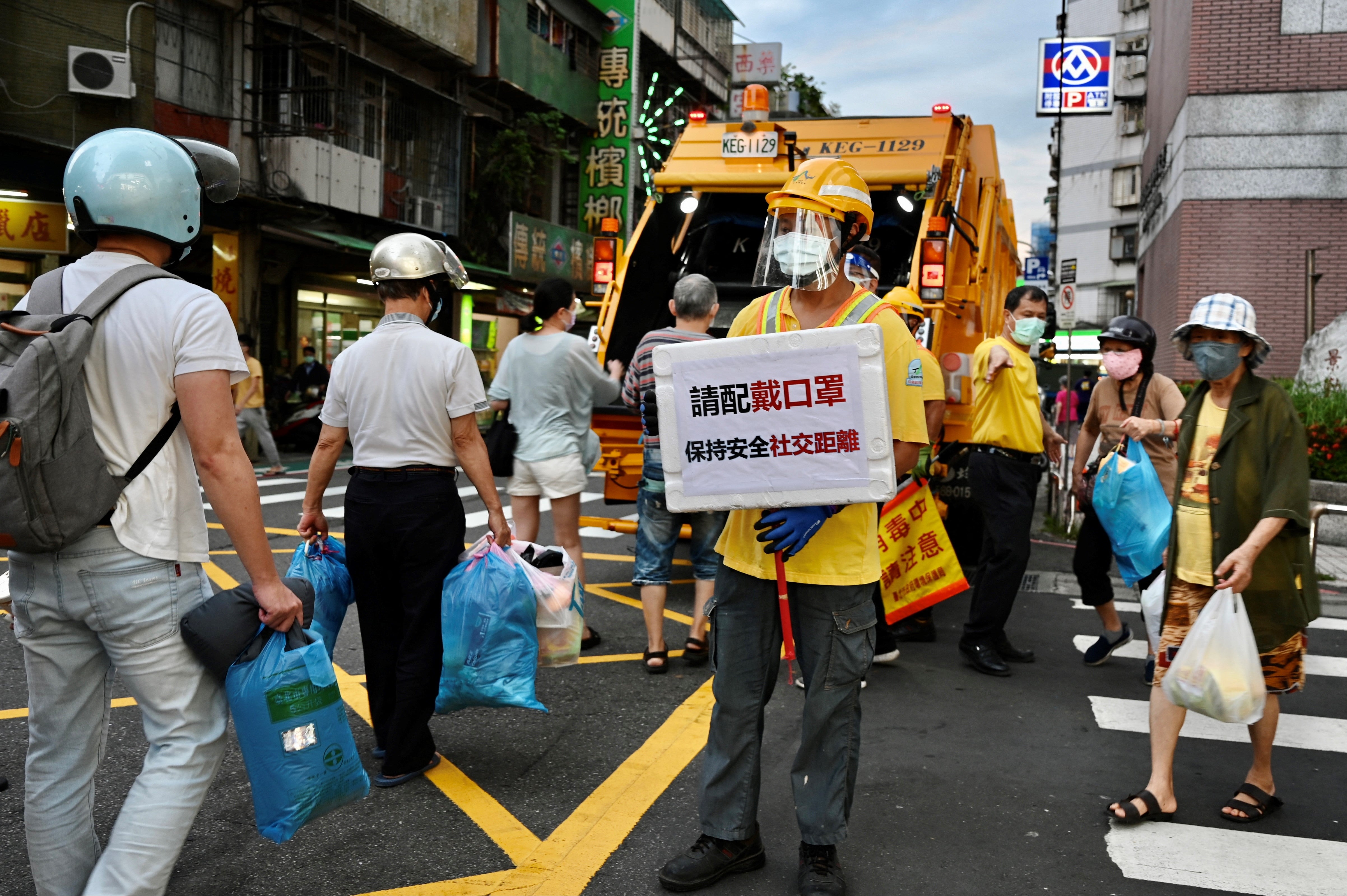 Local residents line up to dump their rubbish into a refuse truck in Taipei
