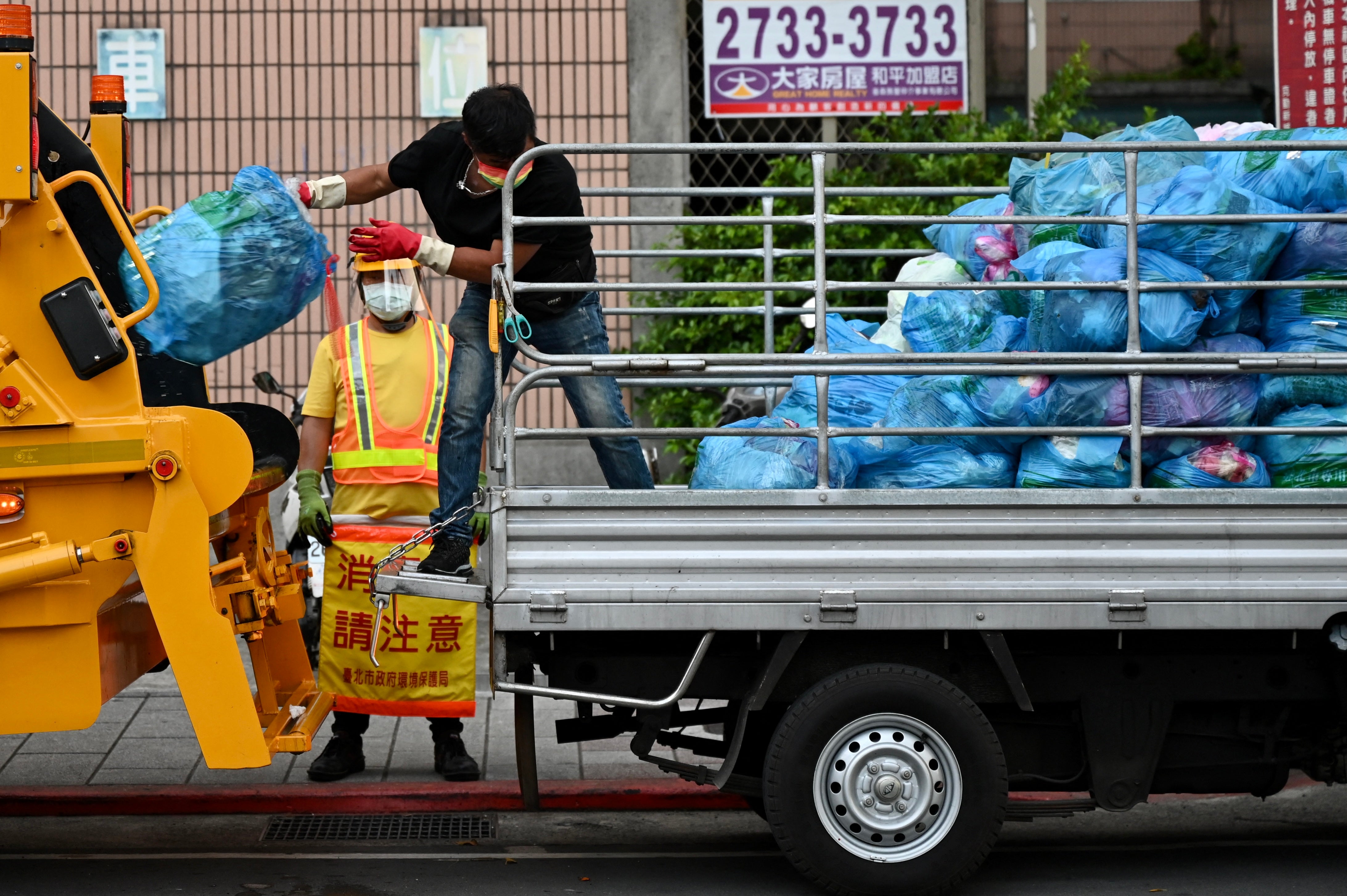 A resident tosses bags of rubbish into a refuse truck in Taipei
