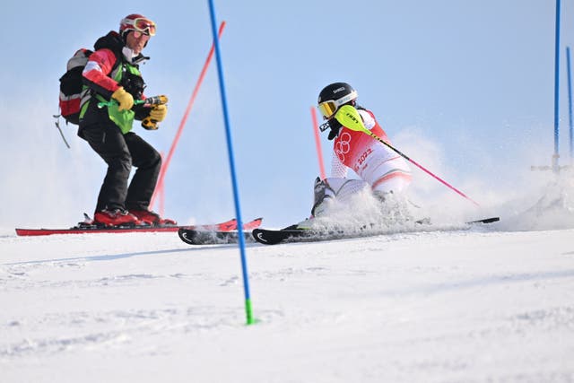 <p>Bulgaria's Eva Vukadinova (R) reacts as a technician is still on the course after leaving a tool on the pole during the first run of the women's slalom during the Beijing 2022 Winter Olympic Games</p>