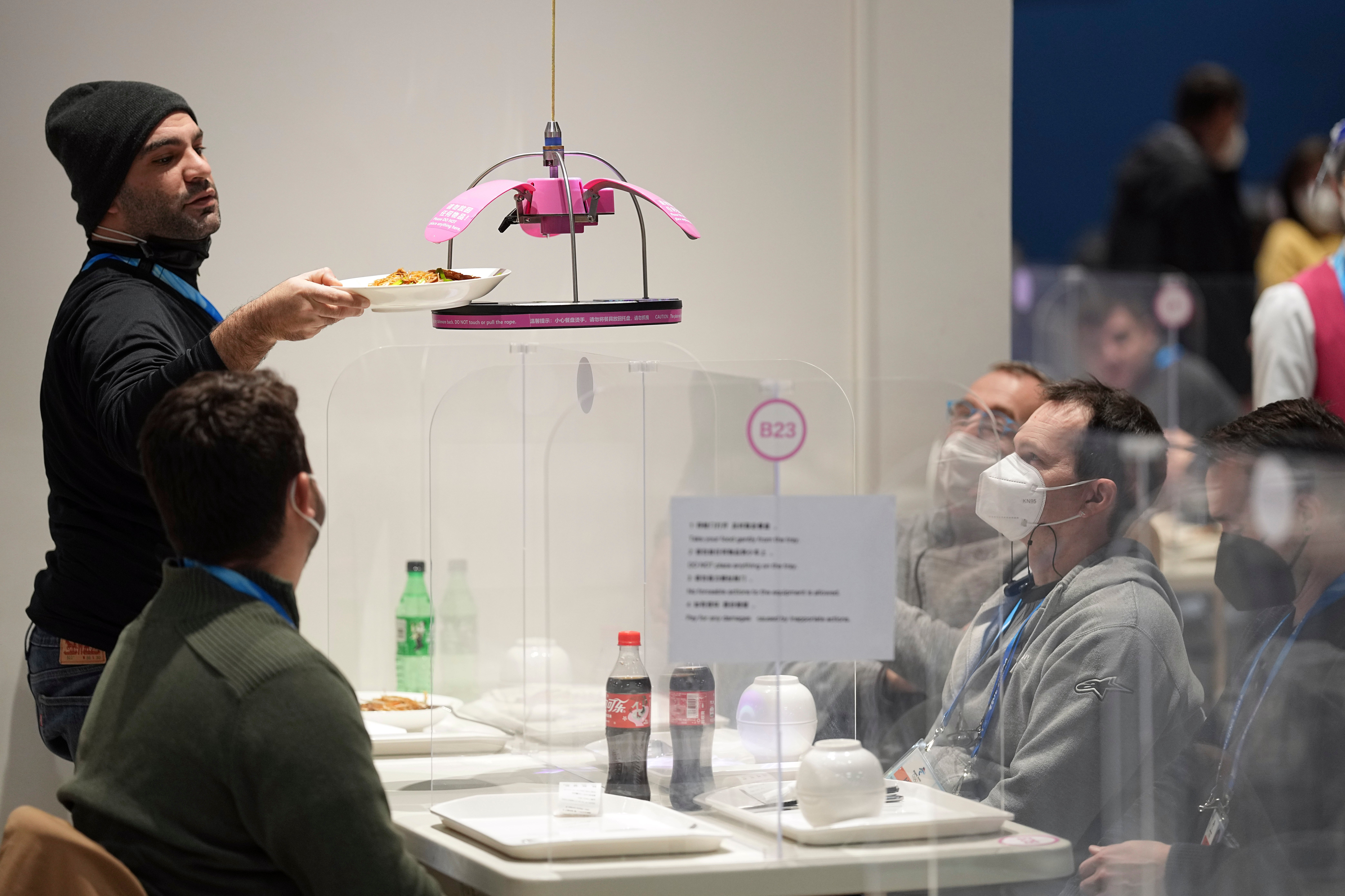 Food is delivered using an automated system to a table at the media dining room during the 2022 Winter Olympics