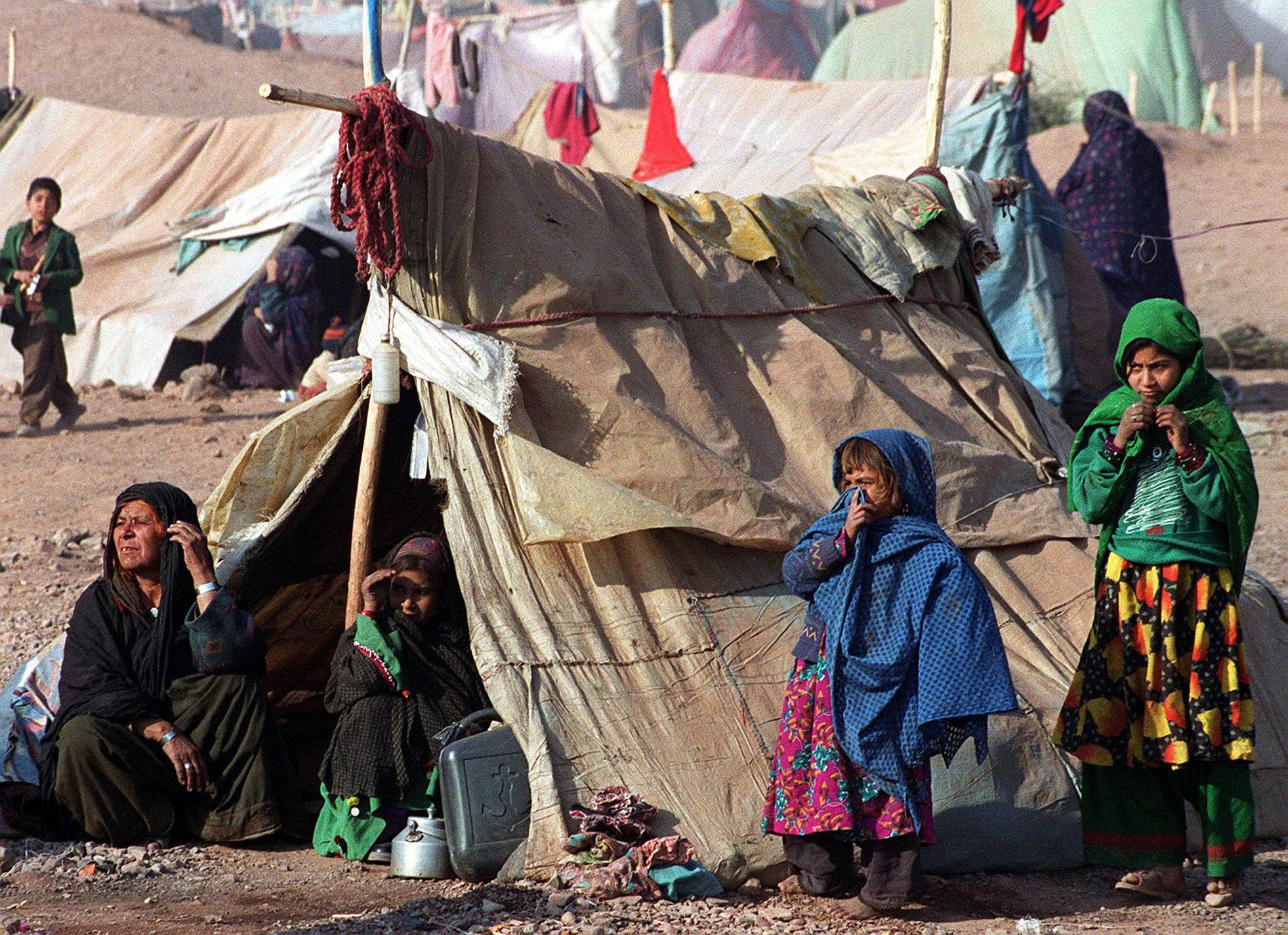 Afghan refugees stay outside their makeshift camps to feel the sun’s heat in Jalozai refugee camp near Peshawar