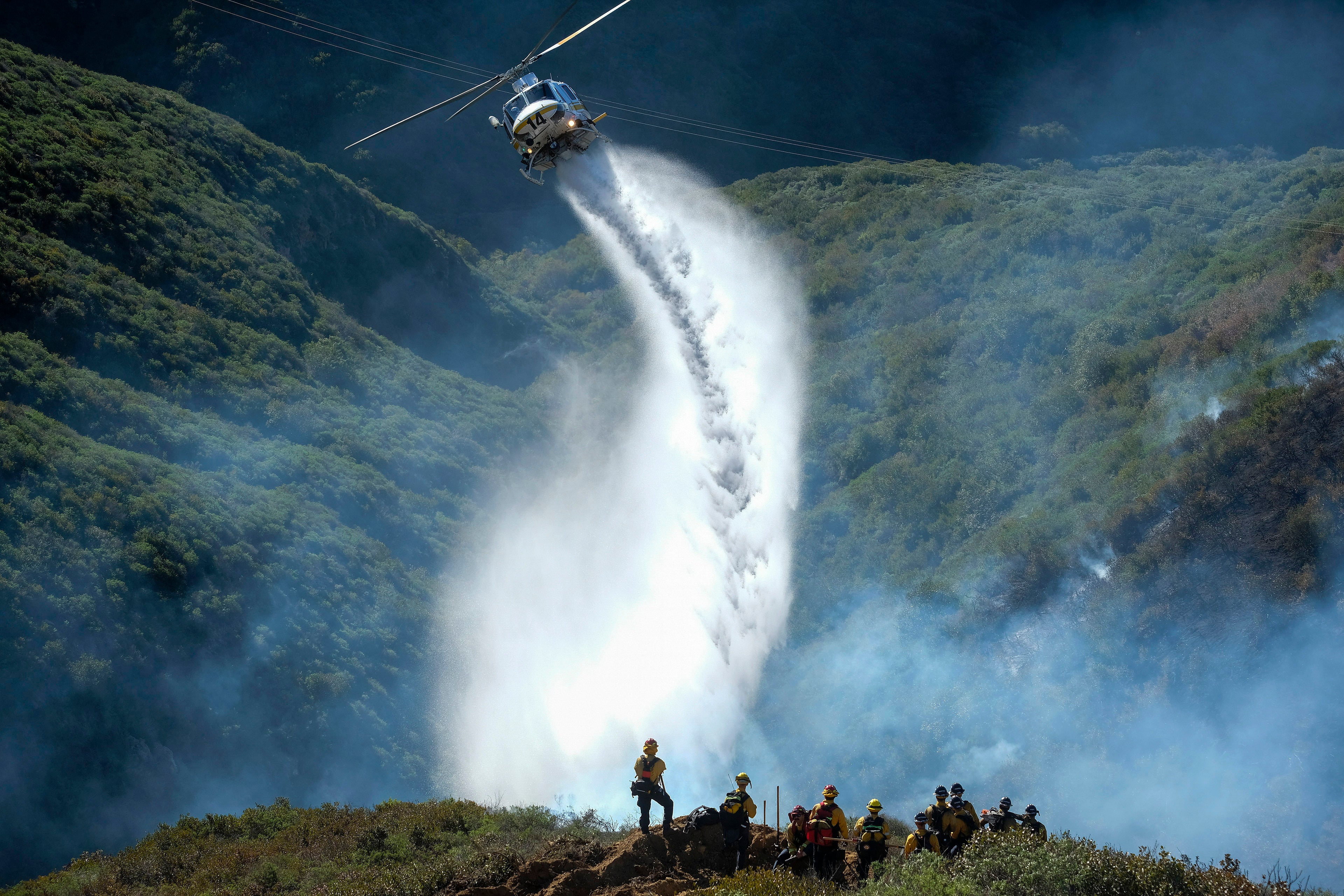 A helicopter dumps water on a hillside in Laguna Beach on 10 February 2022