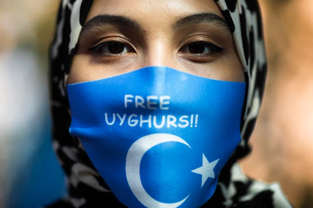 <p>A woman wears a face mask reading 'Free Uyghurs' as she attends a protest during the visit of Chinese Foreign Minister Wang Yi in Berlin, Germany</p>