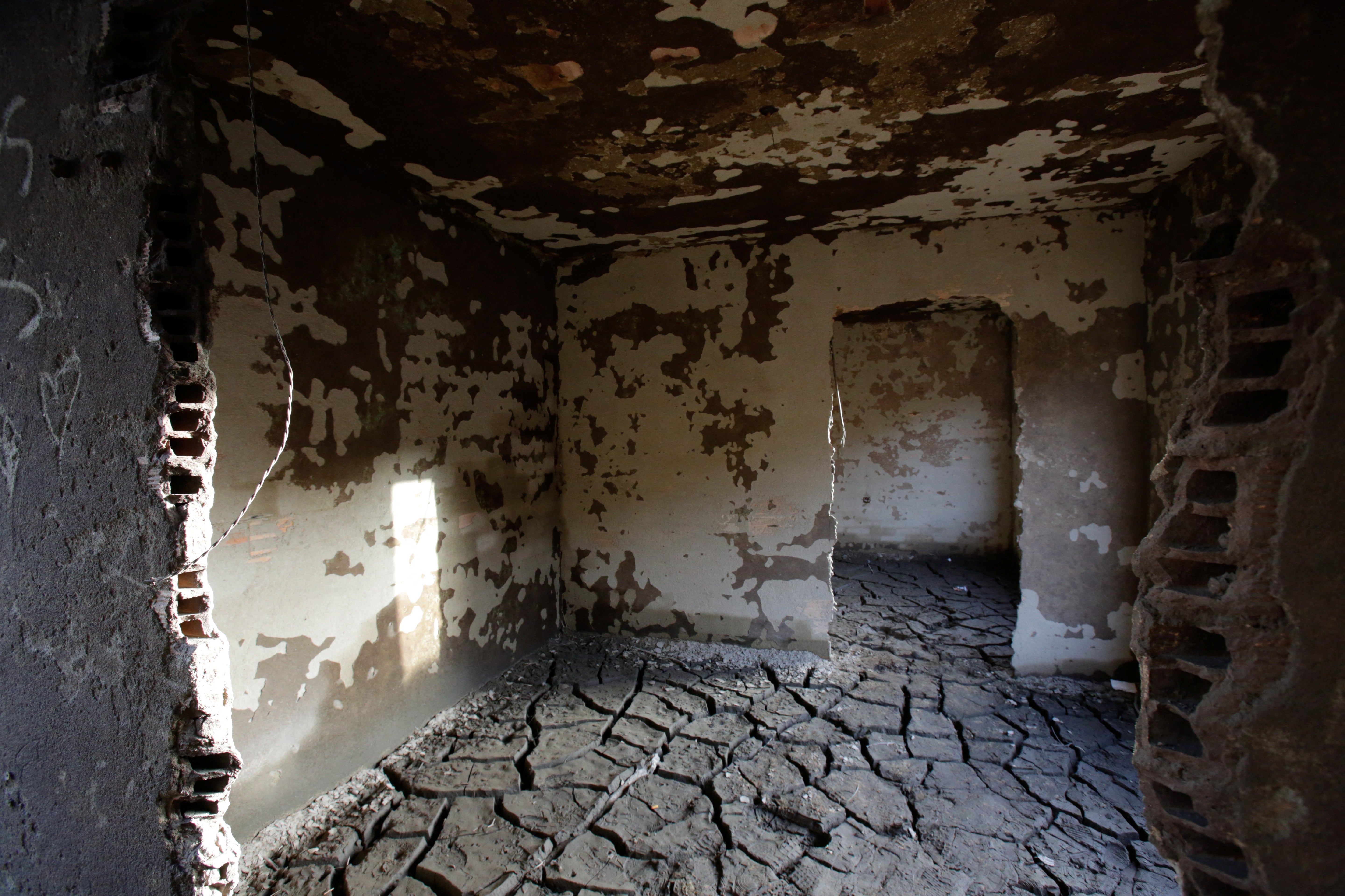 The interior of a house, the muddy ground of which has been cracked by the drought in some spots.