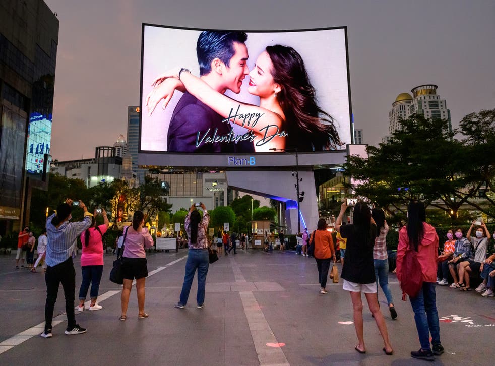 <p>People take photographs of a screen wishing a happy Valentine’s day, in Bangkok on 14 February 2021</p>