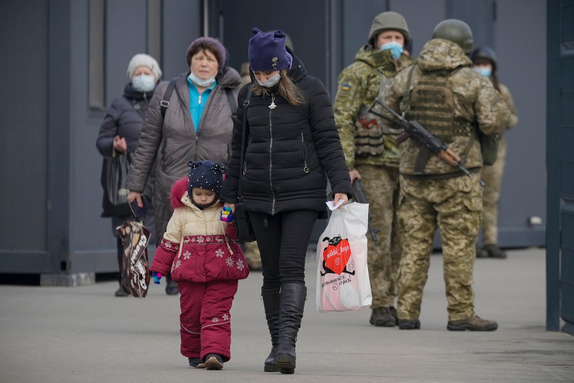 A woman holds a child’s hand as they cross from Ukrainian government to pro-Russian separatist controlled territory in the Luhansk region of eastern Ukraine (Vadim Ghirda/AP)