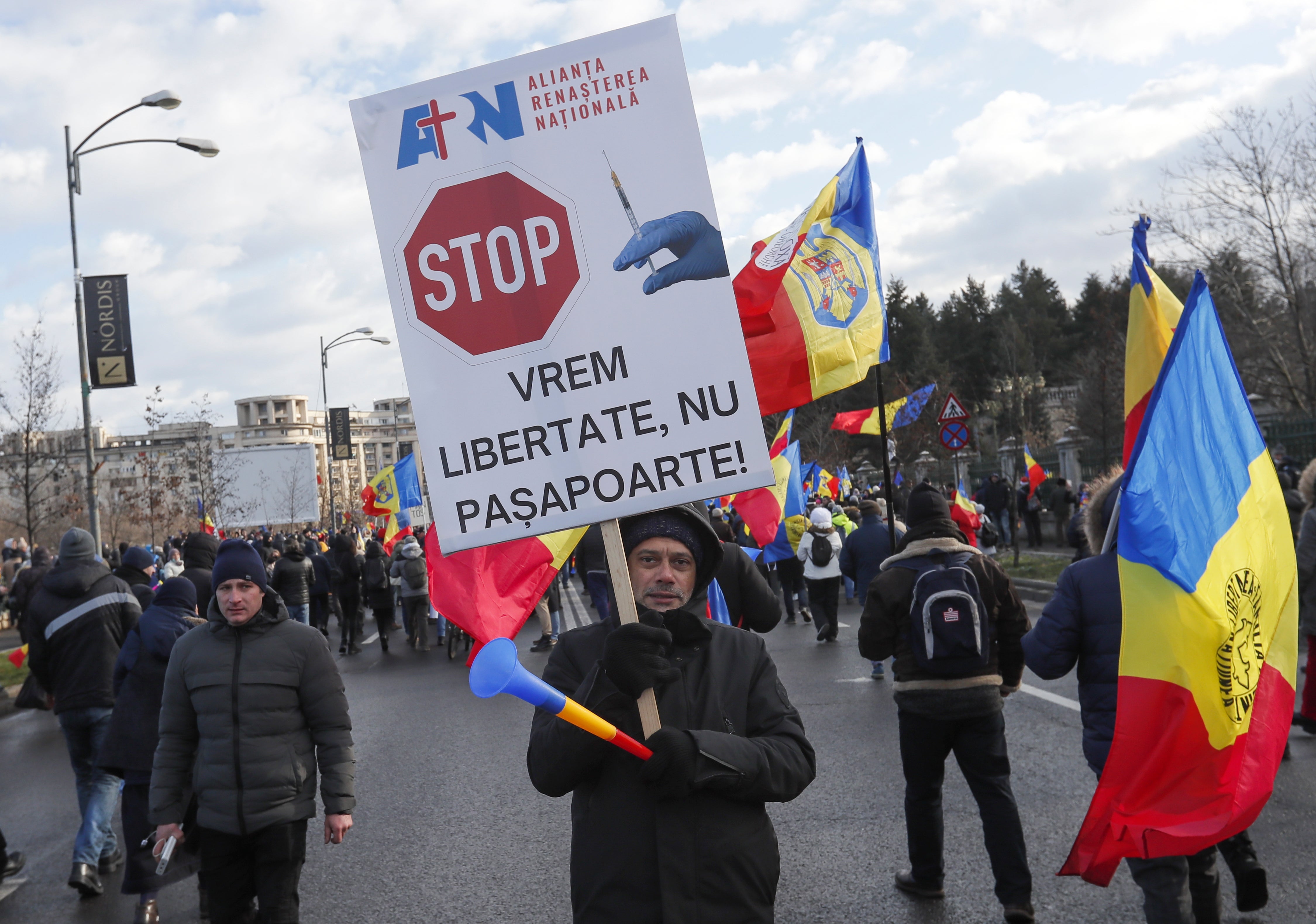 A participant holds a banner reading ‘We want freedom, no passports’ during a rally in front of Bucharest’s parliament building