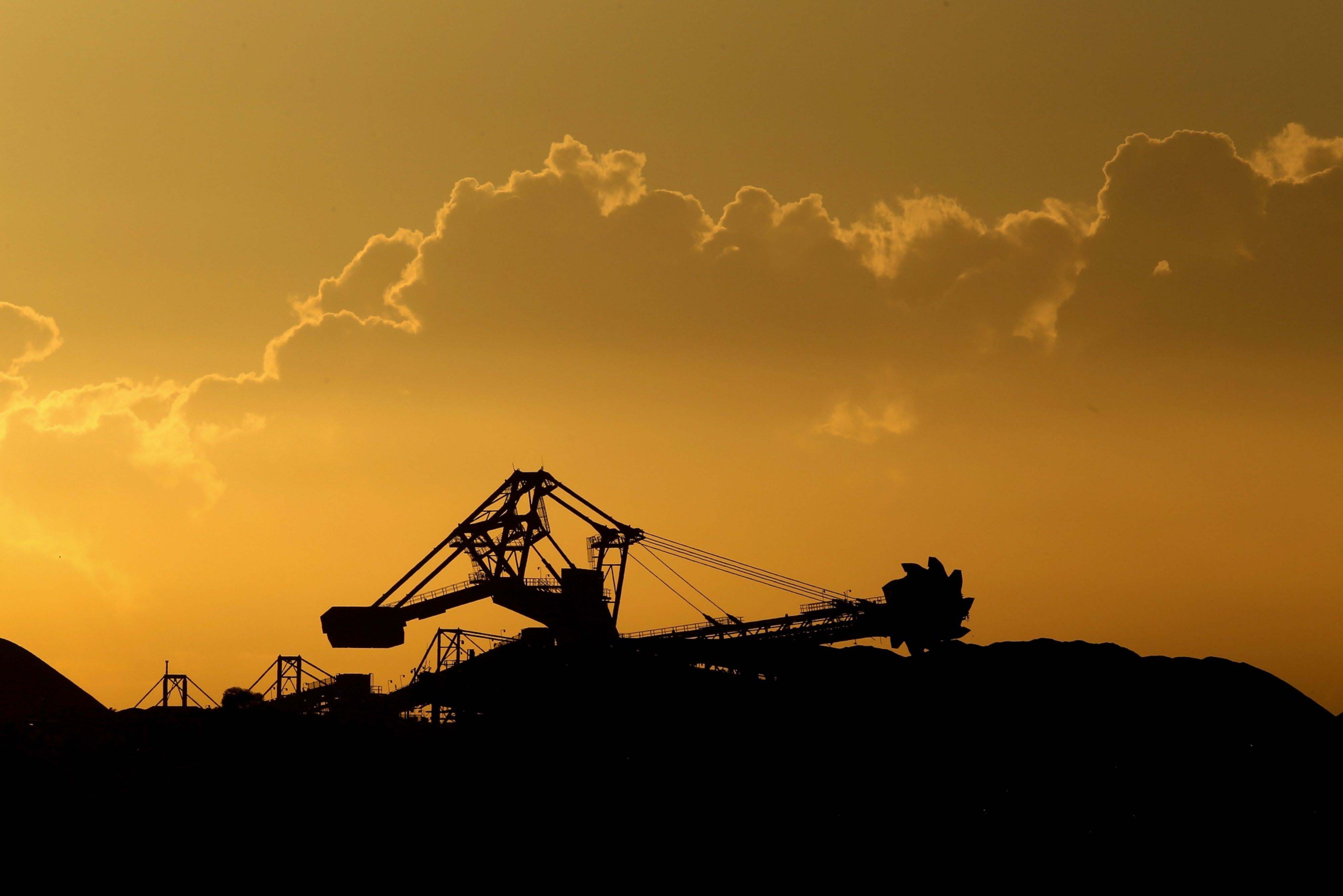 A stacker-reclaimer operates next to stockpiles of coal at the Newcastle Coal Terminal in Newcastle, New South Wales, Australia