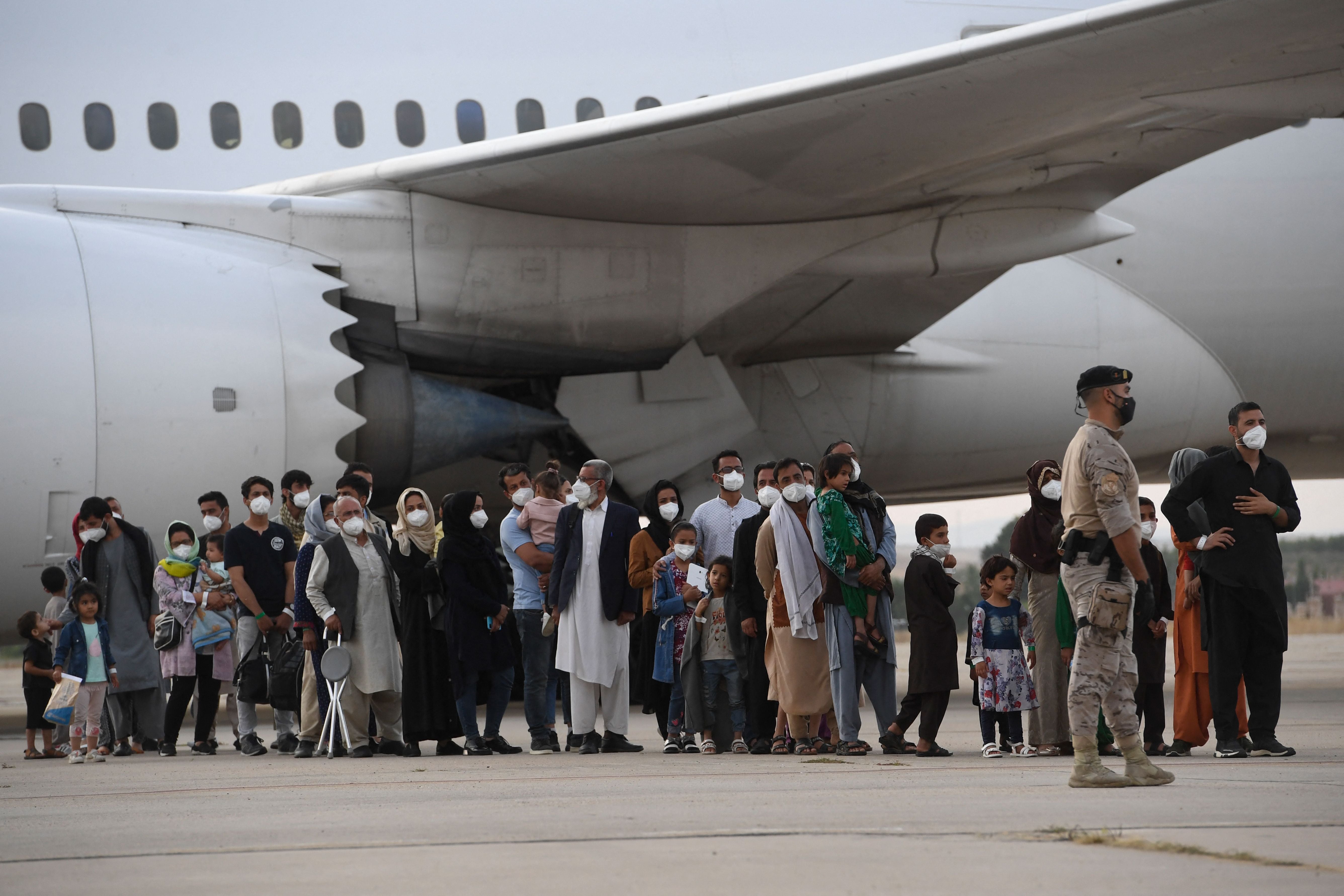 Refugees queue on the tarmac after disembarking from an evacuation flight from Kabul to Madrid on 24 August 2021