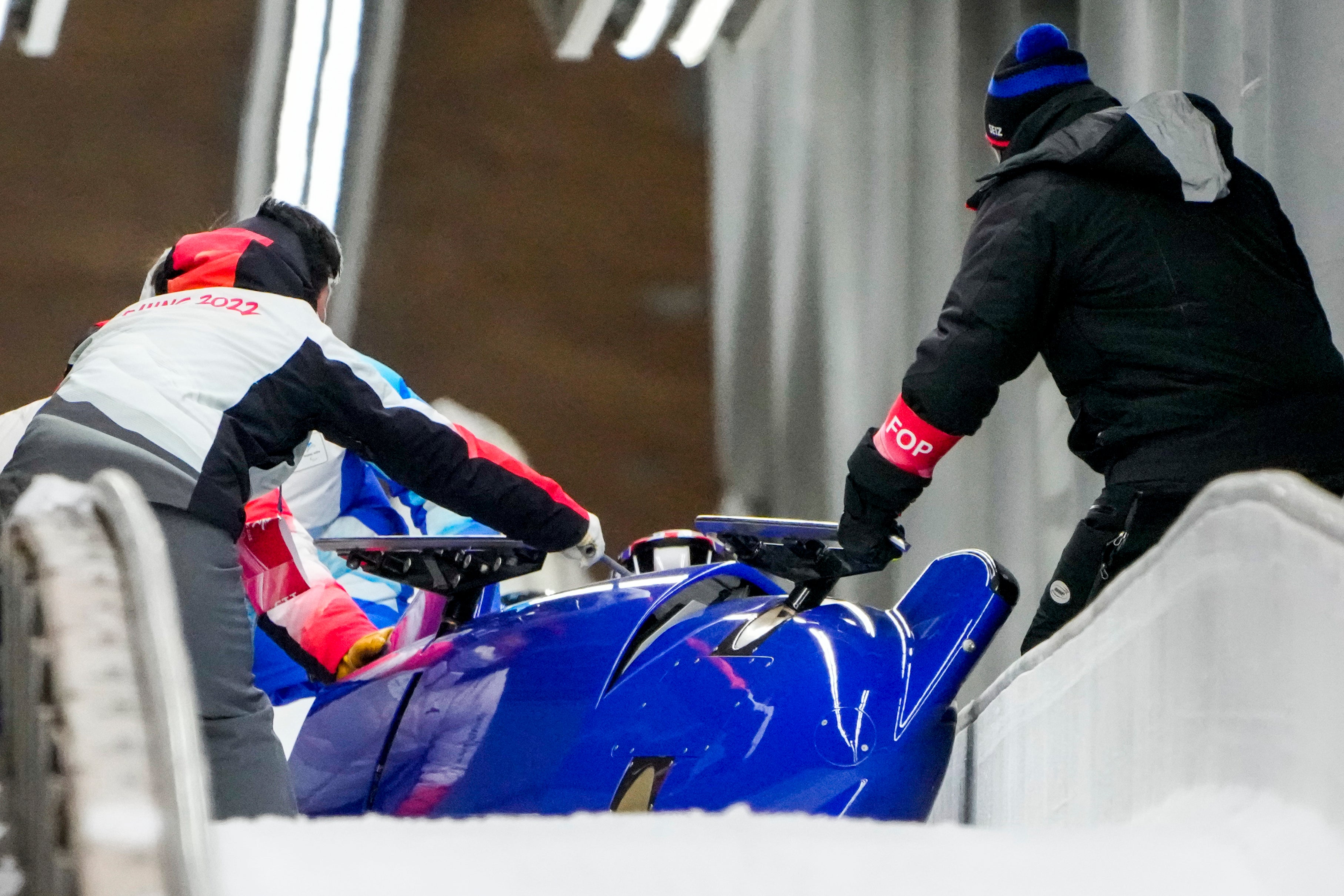 Track assistants tend to the bobsled of Brad Hall and Nick Gleeson
