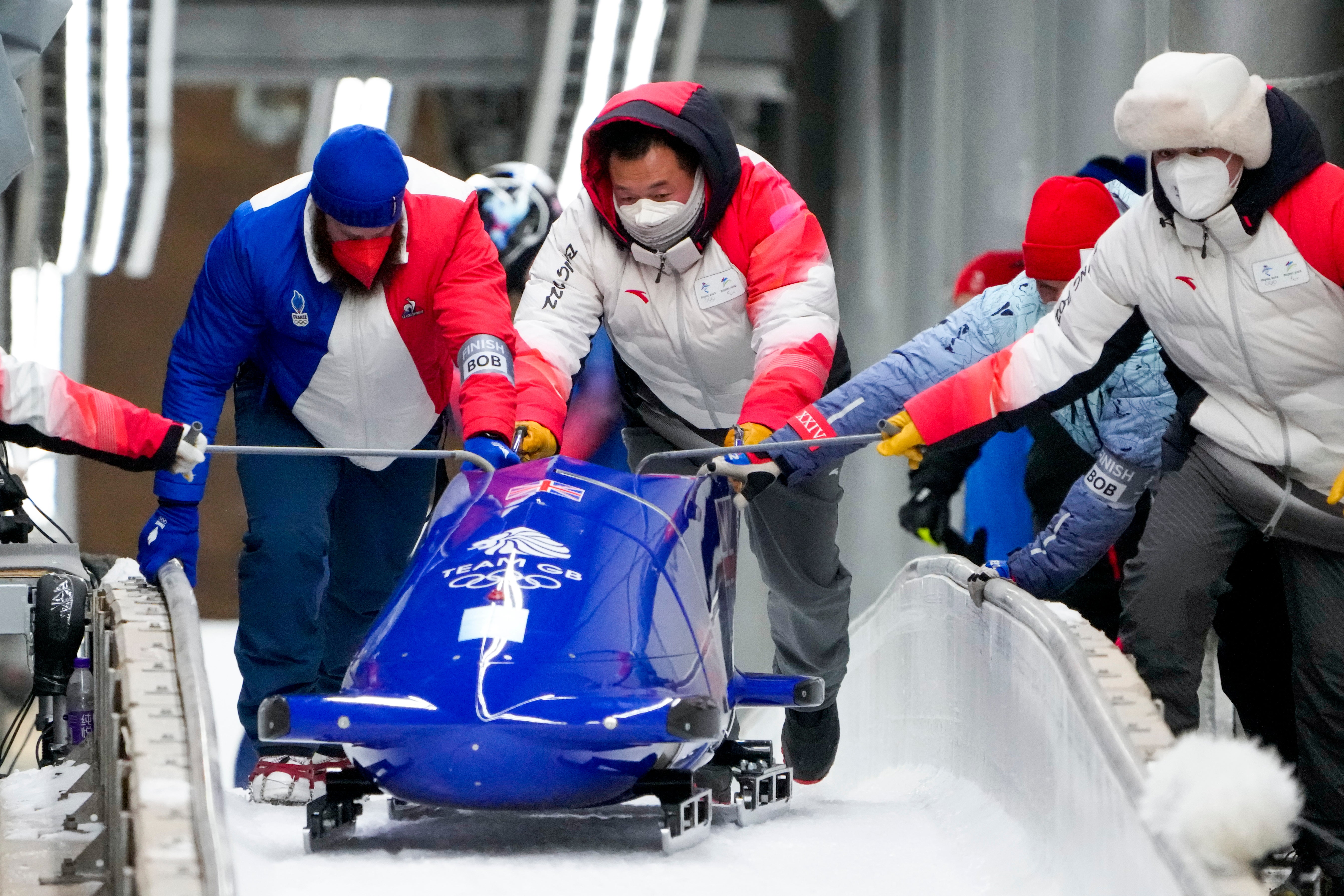 Track assistants push the bobsled of Brad Hall and Nick Gleeson