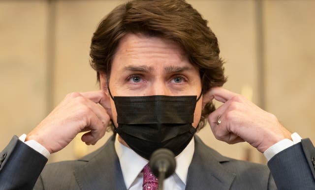 <p>Canadian prime minister Justin Trudeau removes his mask as he arrives at a news conference</p>