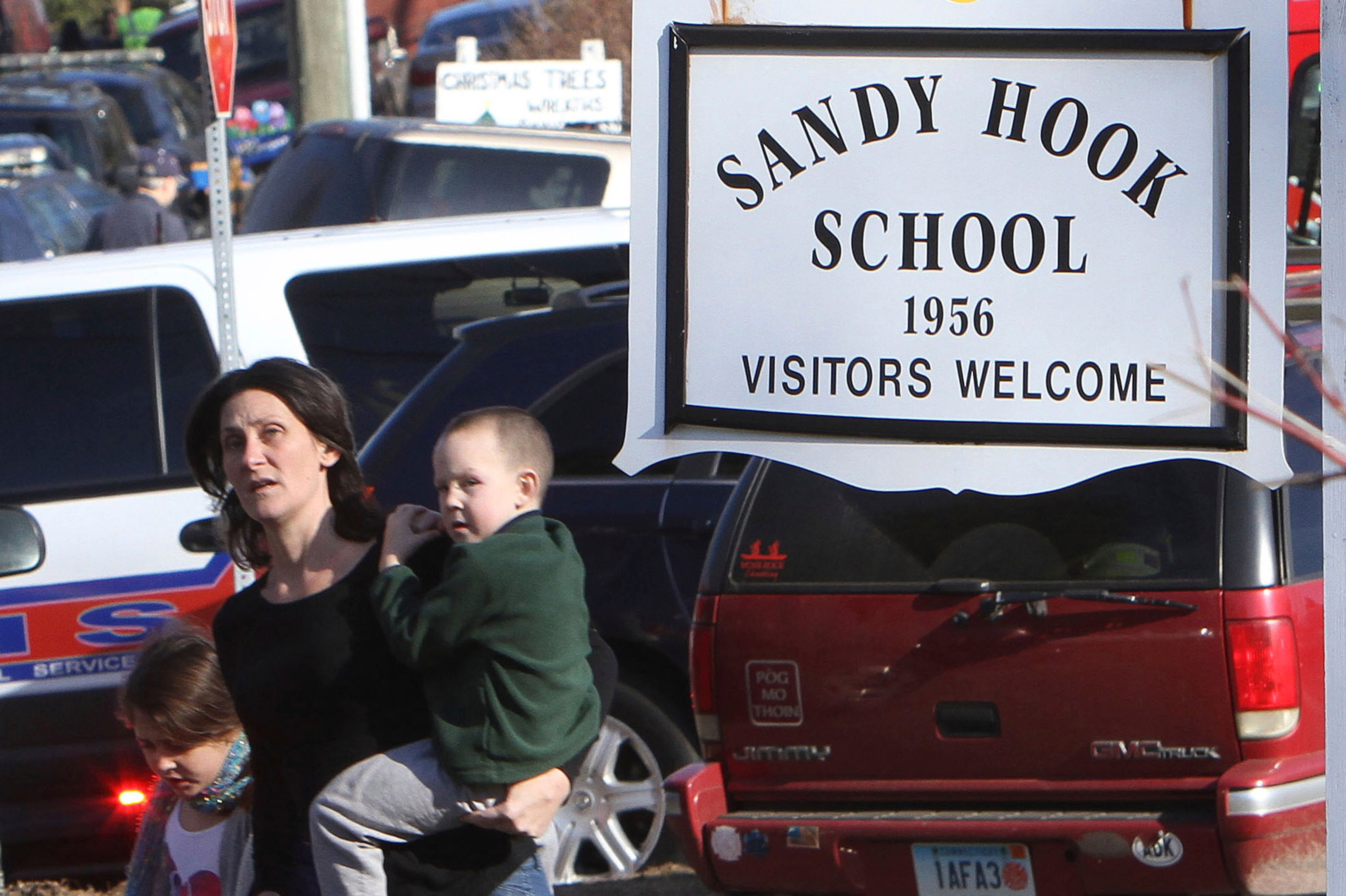 A parent walks away from Sandy Hook Elementary School with her children following the shooting in 2012