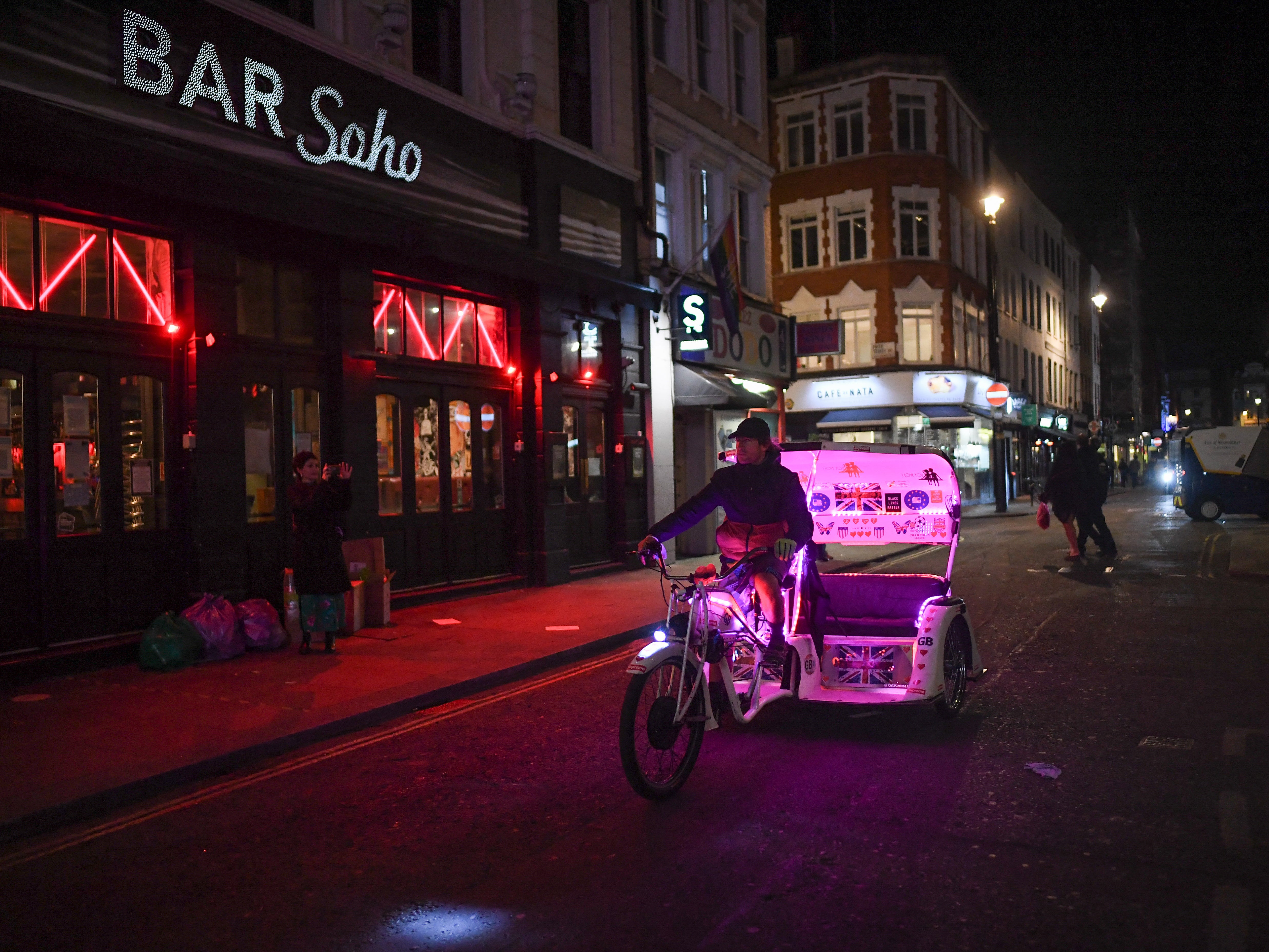 A rickshaw taxi rides past in Soho, London