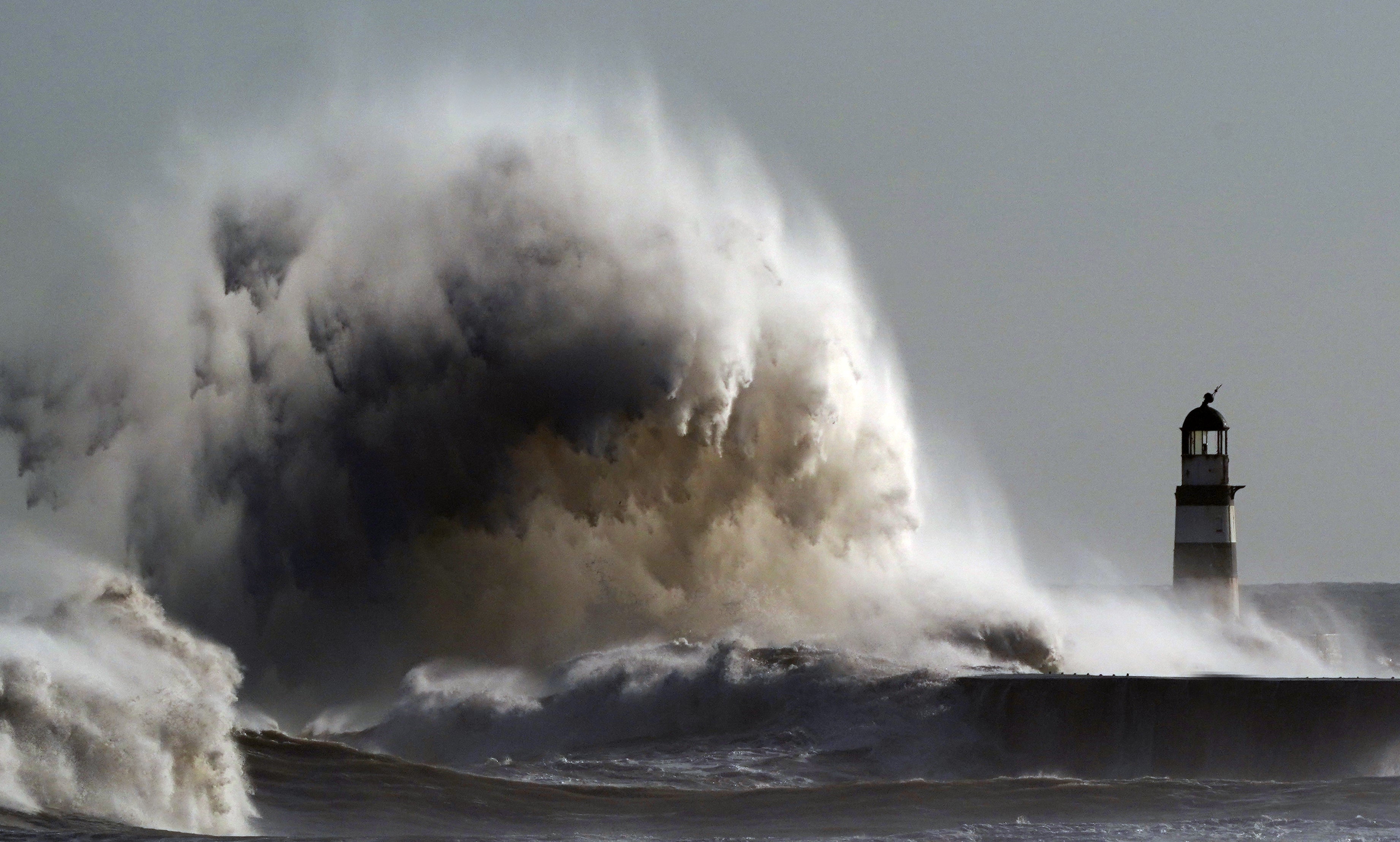 Waves crash against the lighthouse in Seaham Harbour (PA)