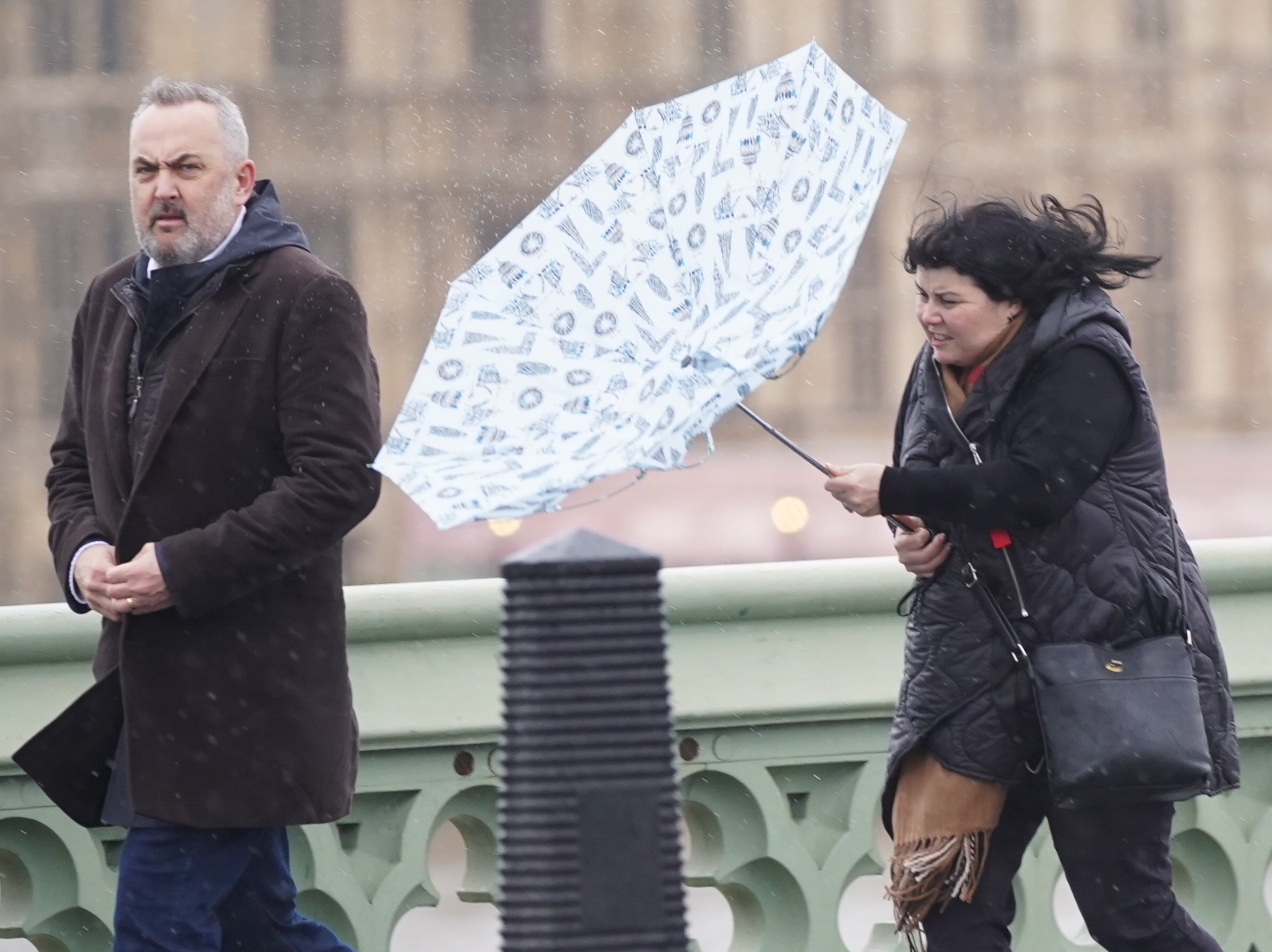 A woman battles with her umbrella on Westminster Bridge, London, in high winds and rain in the capital on 15 February 2022