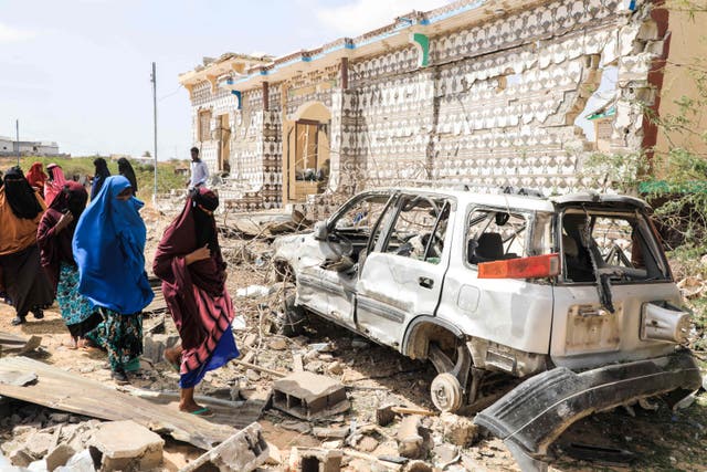 <p>Women walk next to a destroyed house and the wreckage of a car following an explosion provoked by Al-Shabaab militants’ in Mogadishu, Somalia, 16 February 2022</p>