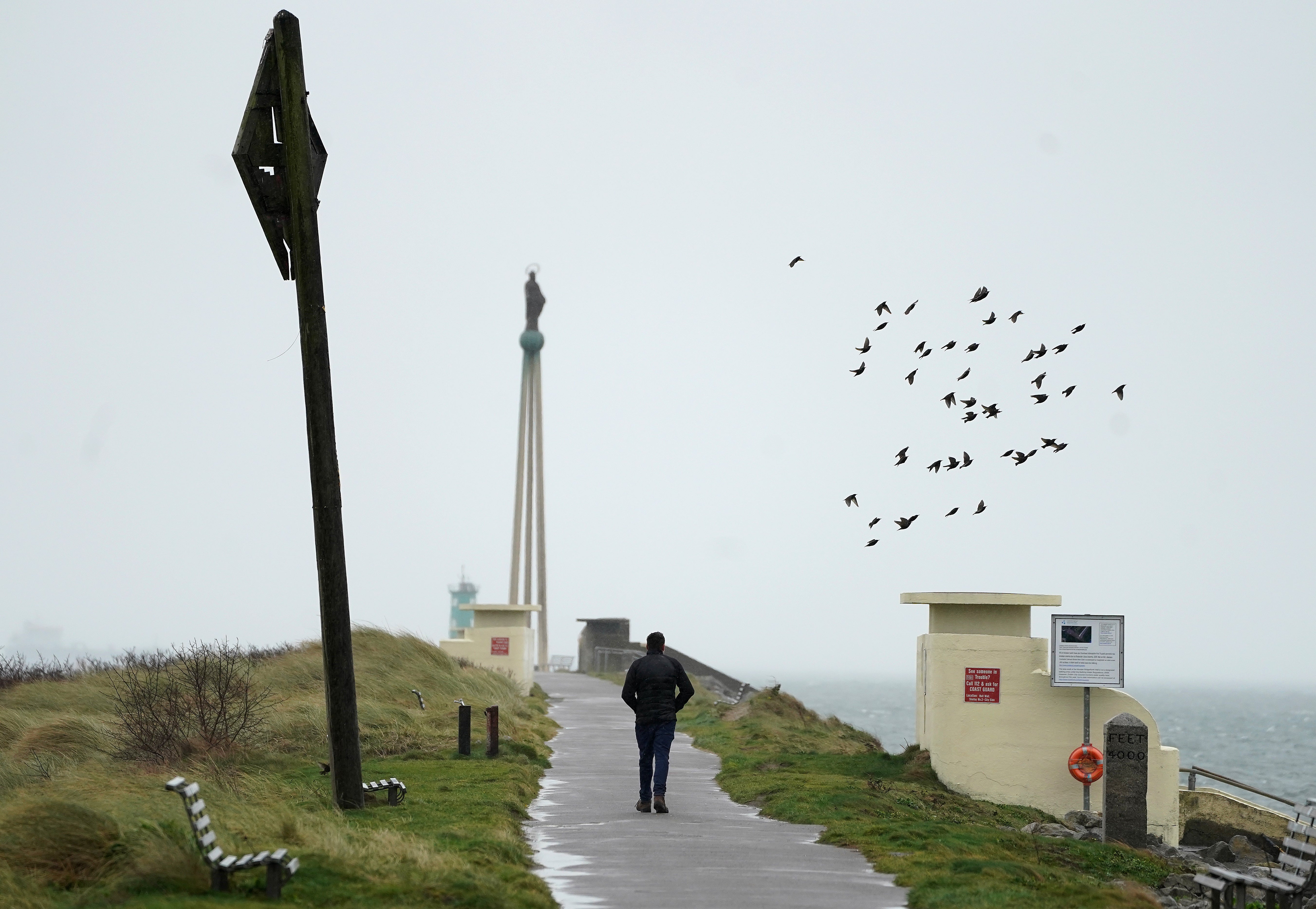 A man walks in strong winds on Bull Wall in Dublin as Storm Dudley makes its way over Ireland (Brian Lawless/PA)