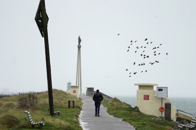 A man walks in strong winds on Bull Wall in Dublin as Storm Dudley makes its way over Ireland (Brian Lawless/PA)