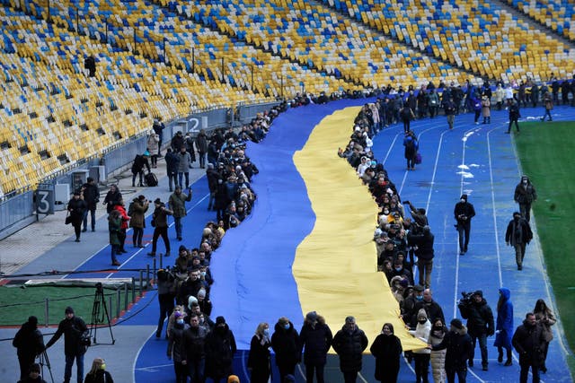 <p>A giant Ukraine flag is unfurled at at a stadium in Kiev on Wednesday to mark a ‘Day of Unity’ amid the threat of a Russian invasion</p>