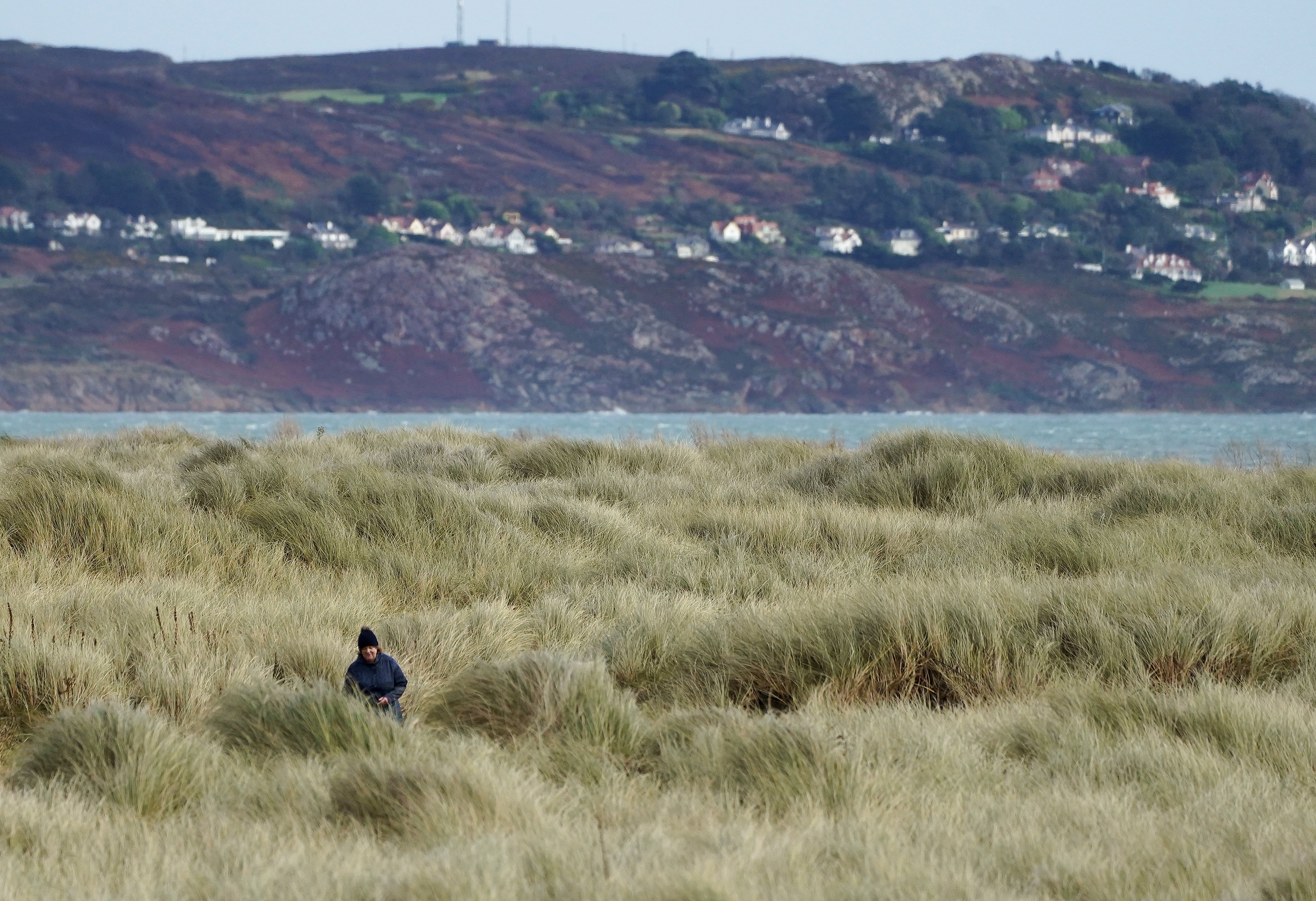 A woman goes for a walk in strong winds on Bull Island (Brian Lawless/PA)