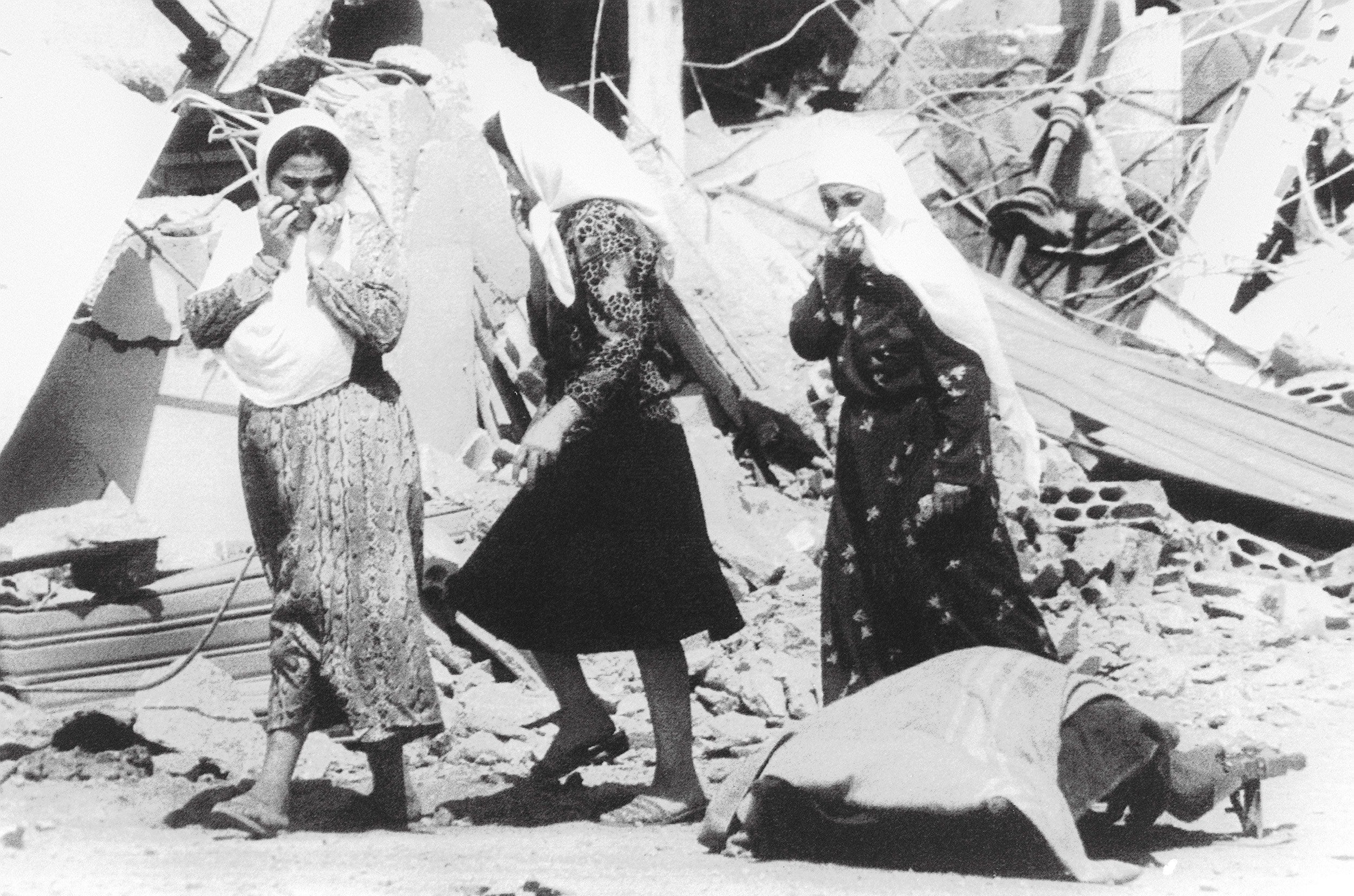 Three Palestinian women pass the body of one of the victims of the massacre in Sabra