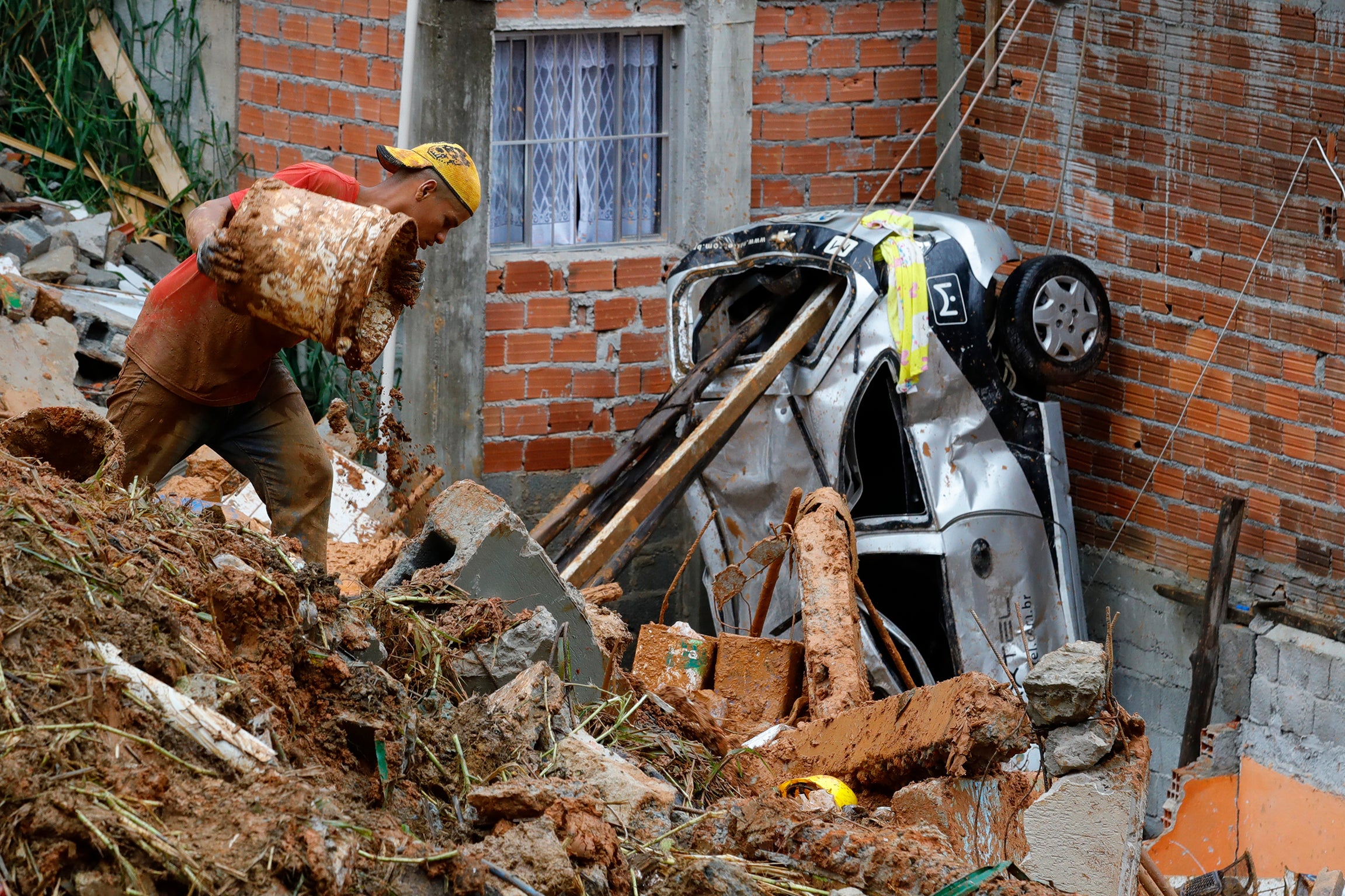 A volunteer searches for people in the rubble after heavy rain triggered a landslide in Franco da Rocha, Sao Paulo state, Brazil, Monday, January 31, 2022