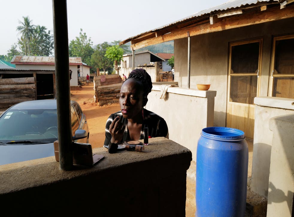 <p>Va-Bene Elikem Fiatsi, 40, a trans woman applies make-up before attending the funeral of her grandmother in her family's village in Ghana</p>