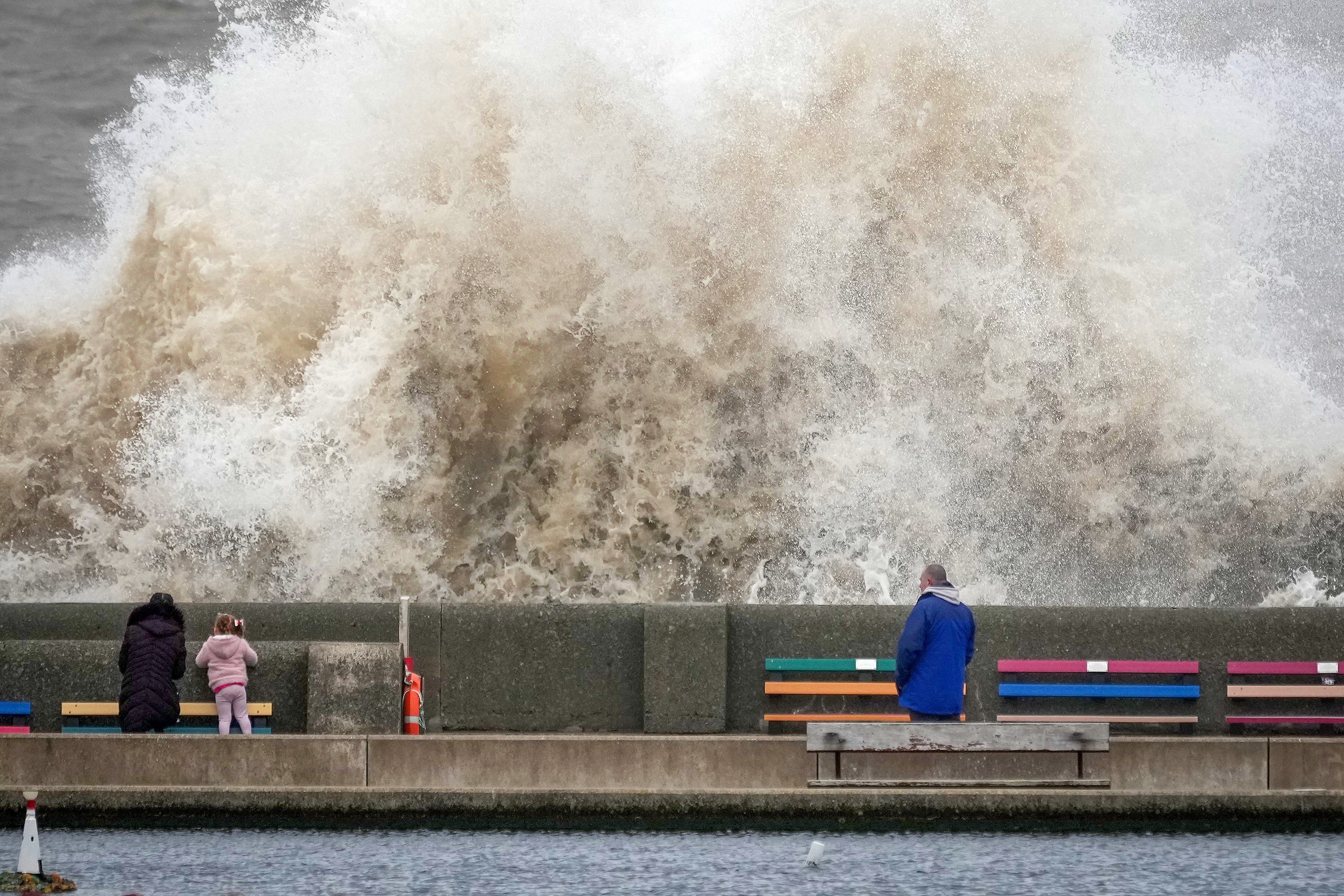 People view the waves created by high winds and spring tides hitting the sea wall at New Brighton promenade on 17 February 2022 in Liverpool