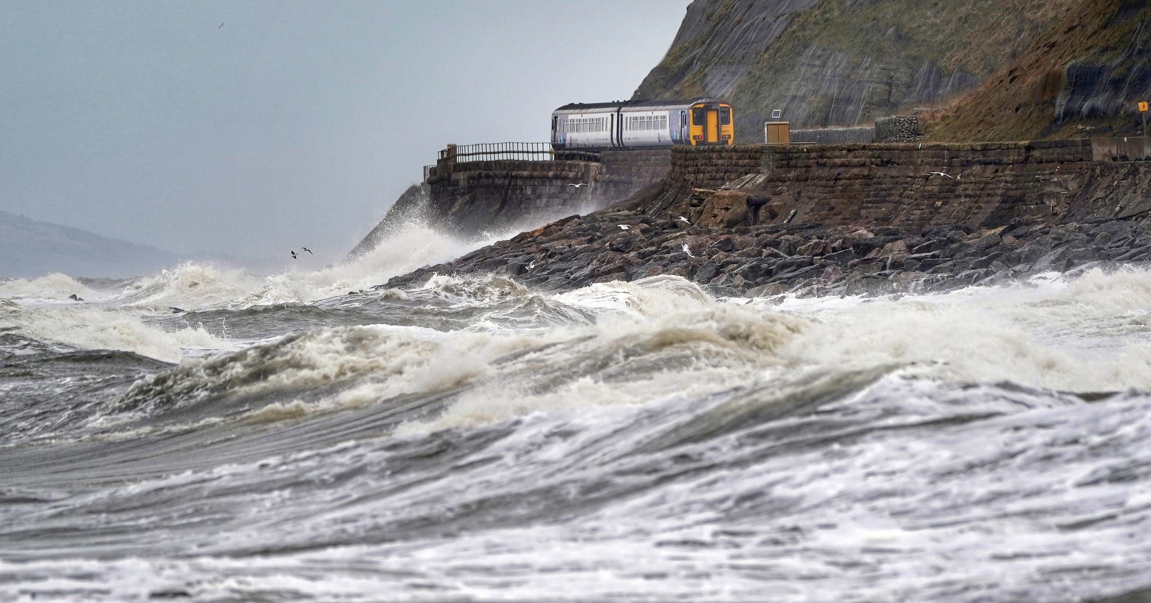 A train heads along the west coast between Whitehaven and Carlisle after Storm Dudley hit the north of the country last night