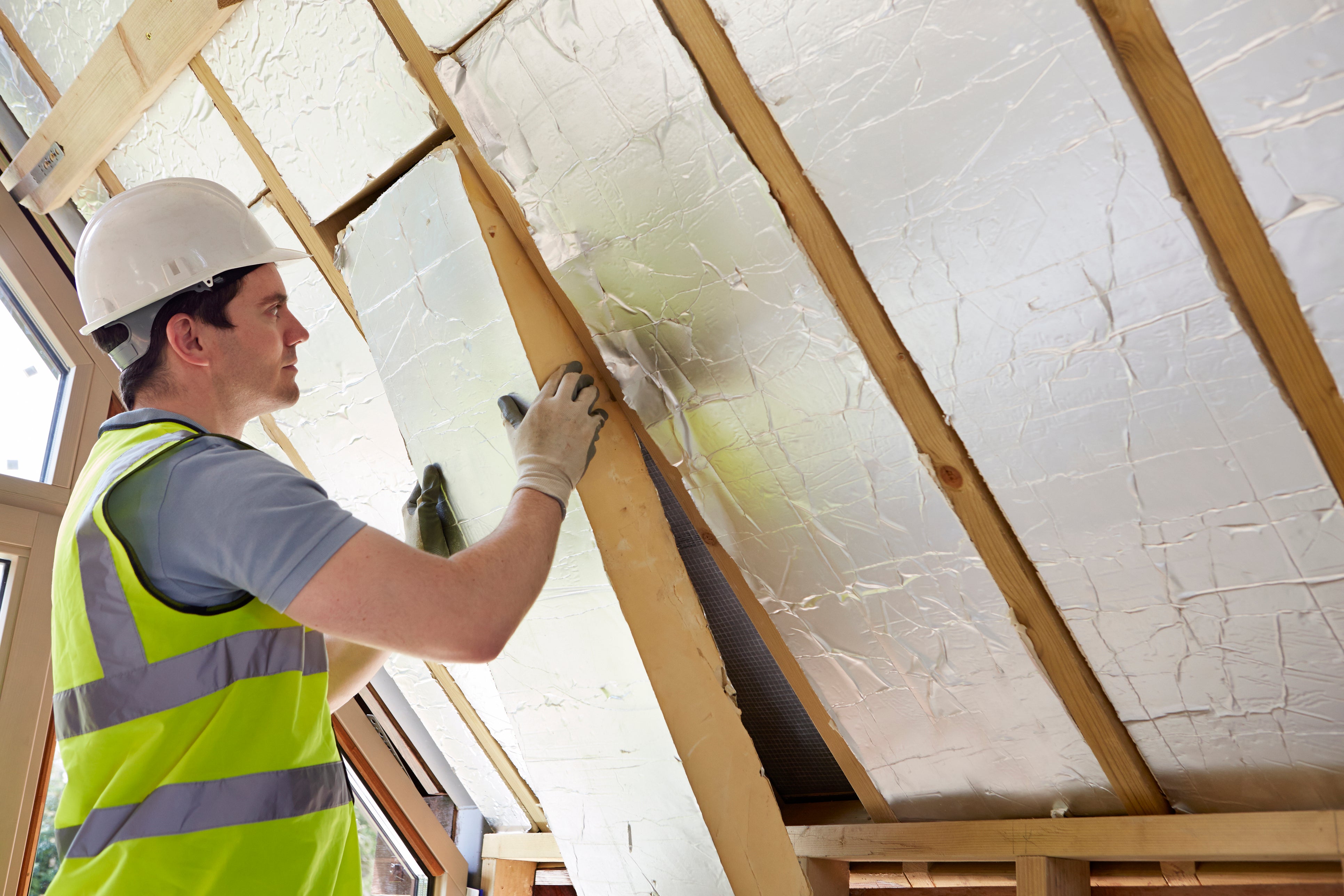 Builder fitting insulation into the roof of a new home