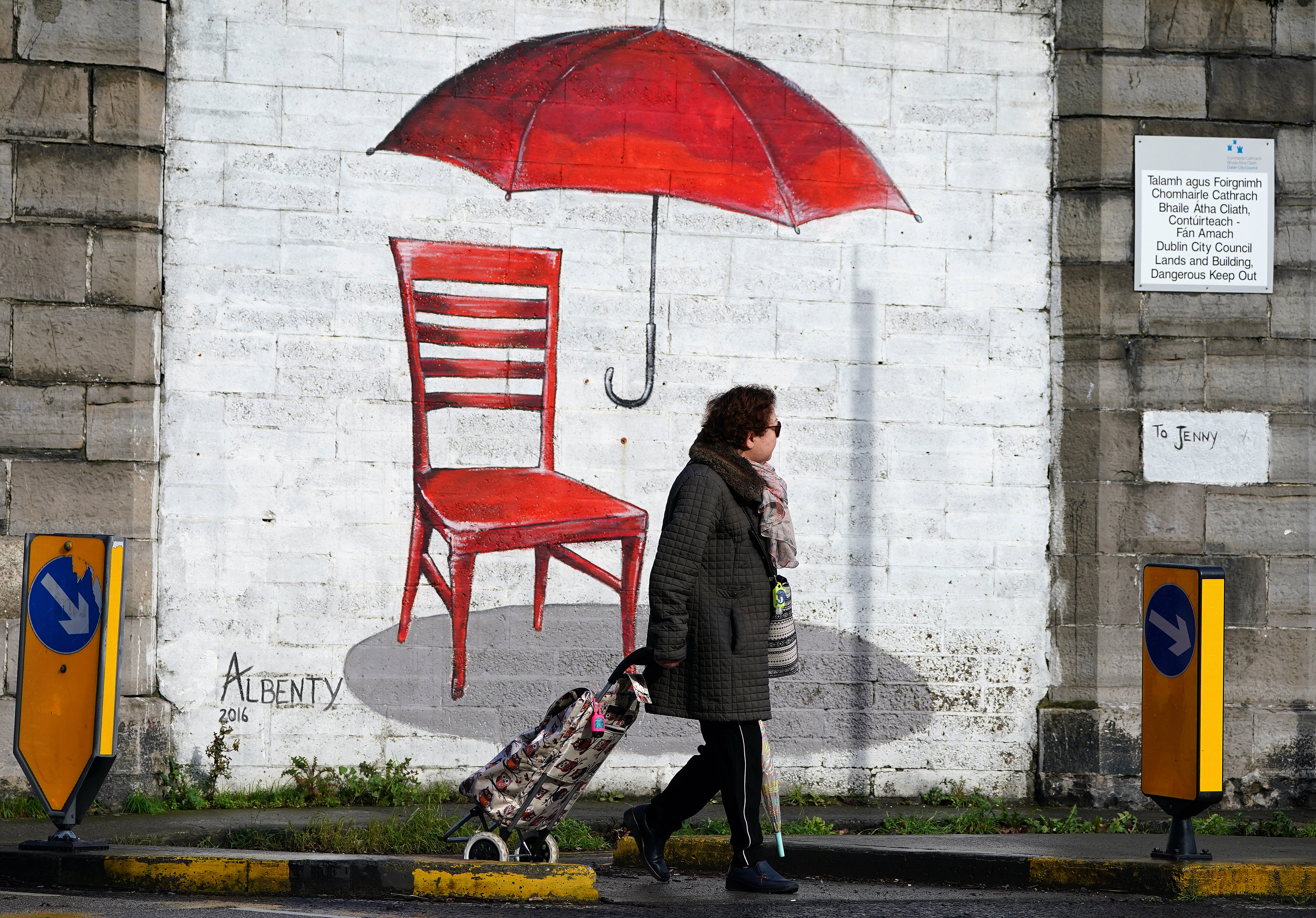 A woman walks past a mural of a red umbrella in Dublin as schools and colleges in nine counties in the Republic of Ireland are closed on Friday (Brian Lawless/PA)