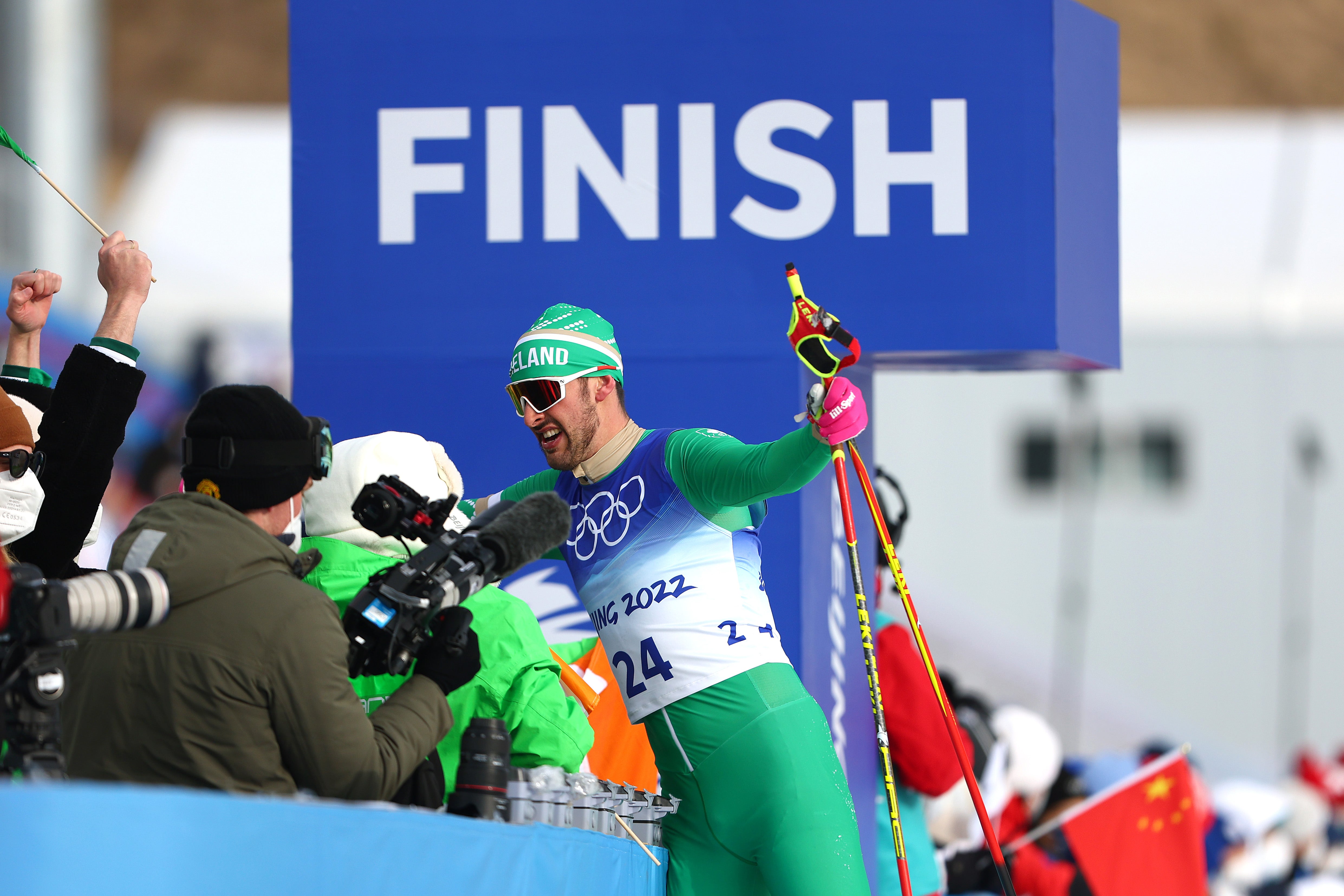 Thomas Maloney Westgaard of Team Ireland reacts with their team after finishing during the Men's Cross-Country Skiing 15km Classic on Day 7 of Beijing 2022 Winter Olympics