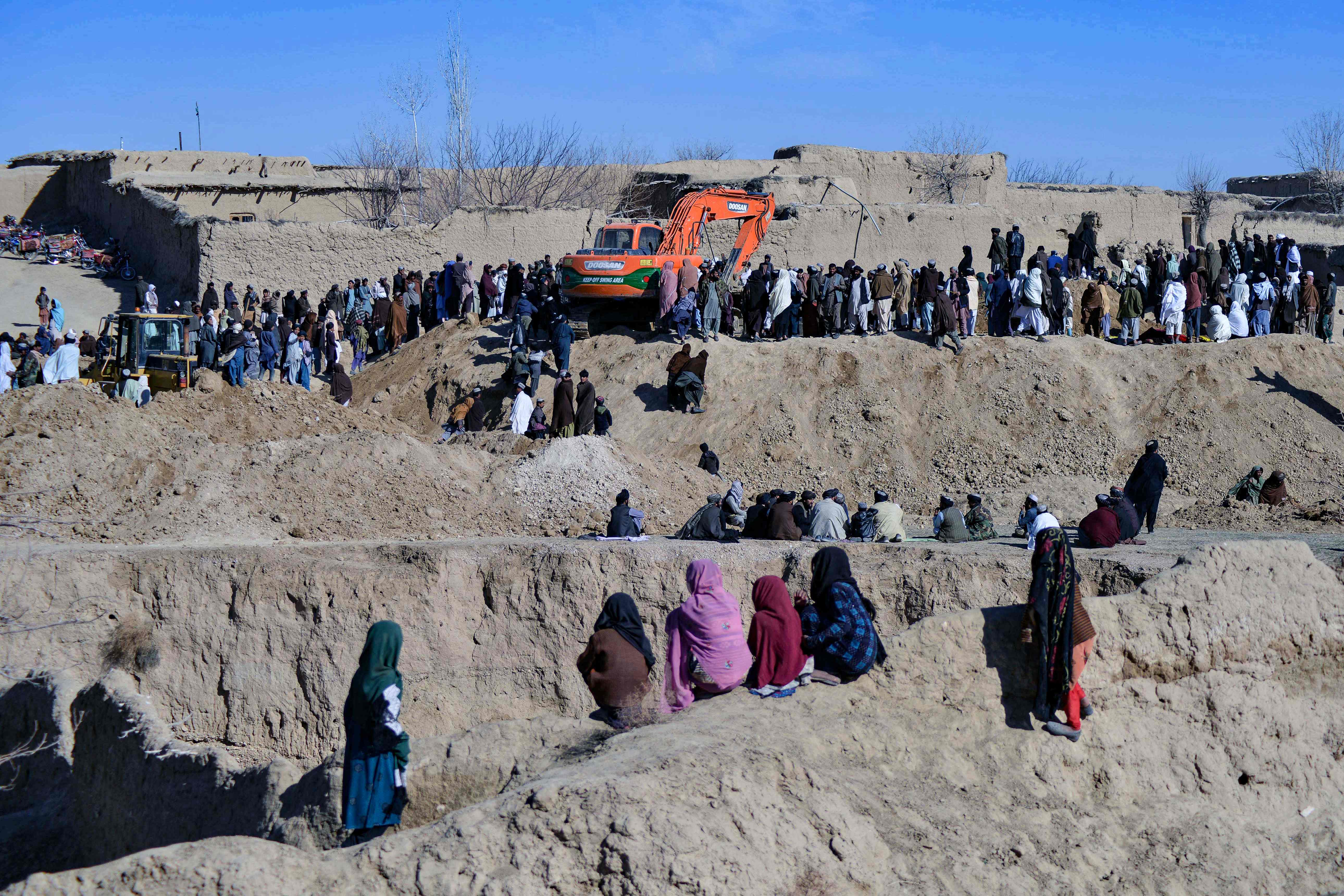 Afghans gather as rescuers try to reach and rescue a boy trapped for days in a well in the remote village of Shokak
