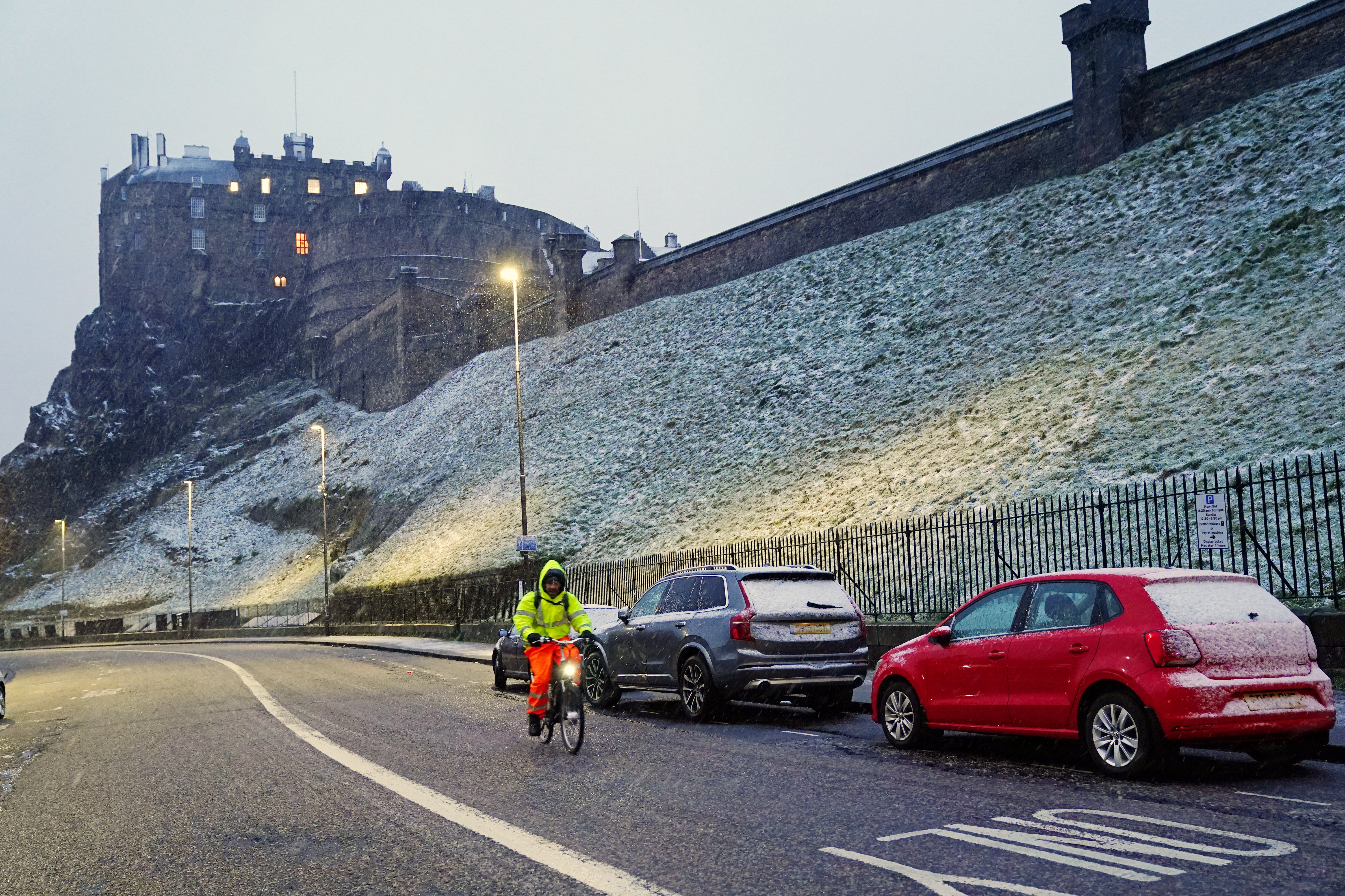 A cyclist rides along a road in falling snow near Edinburgh Castle as Storm Eunice sweeps across the UK (Jane Barlow/PA)