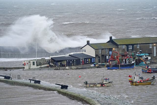 Waves crash over the sea wall at the harbour in Lyme Regis in Dorset (Andrew Matthews/PA)