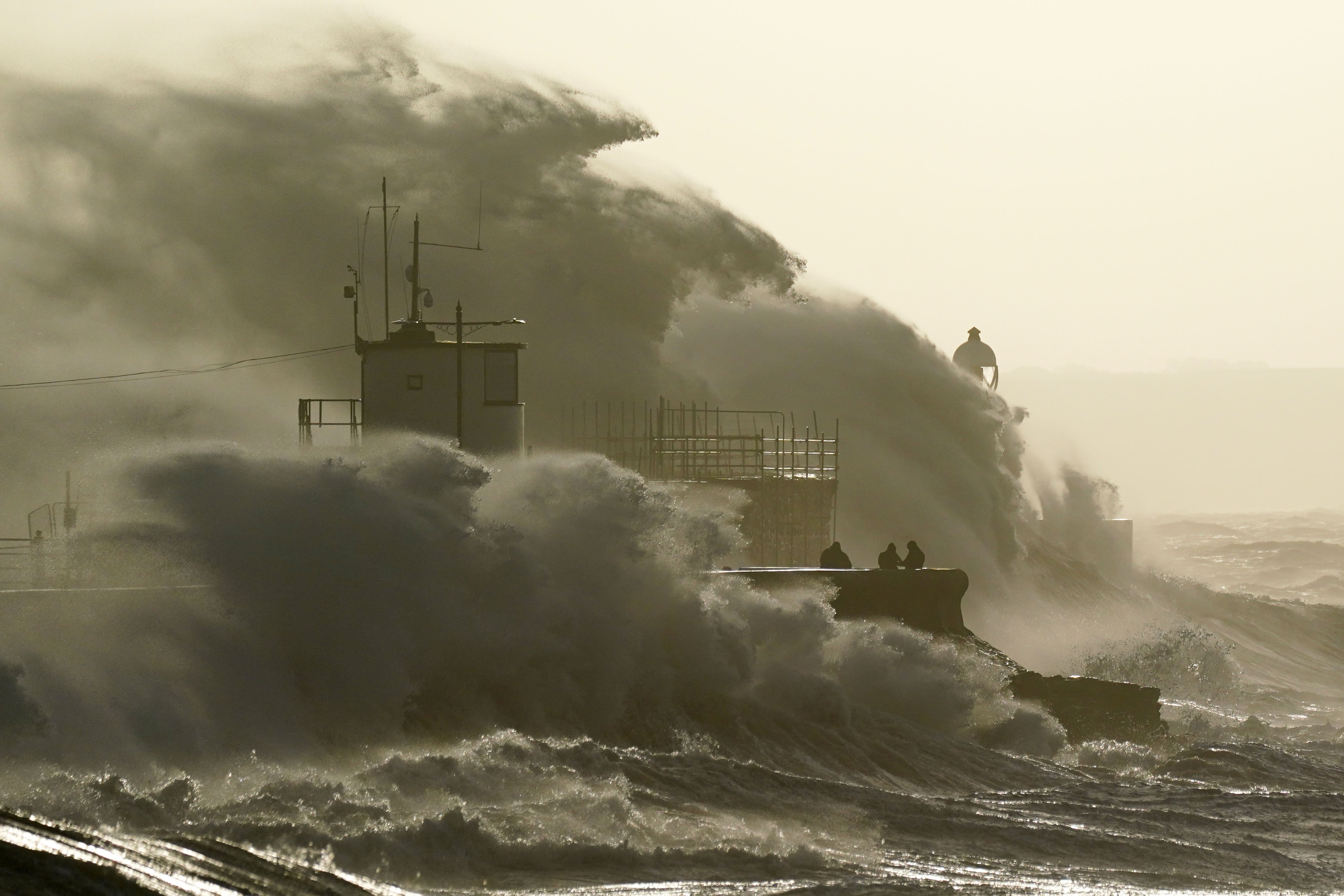 Waves crash against the sea wall and Porthcawl Lighthouse in Bridgend (Jacob King/PA)