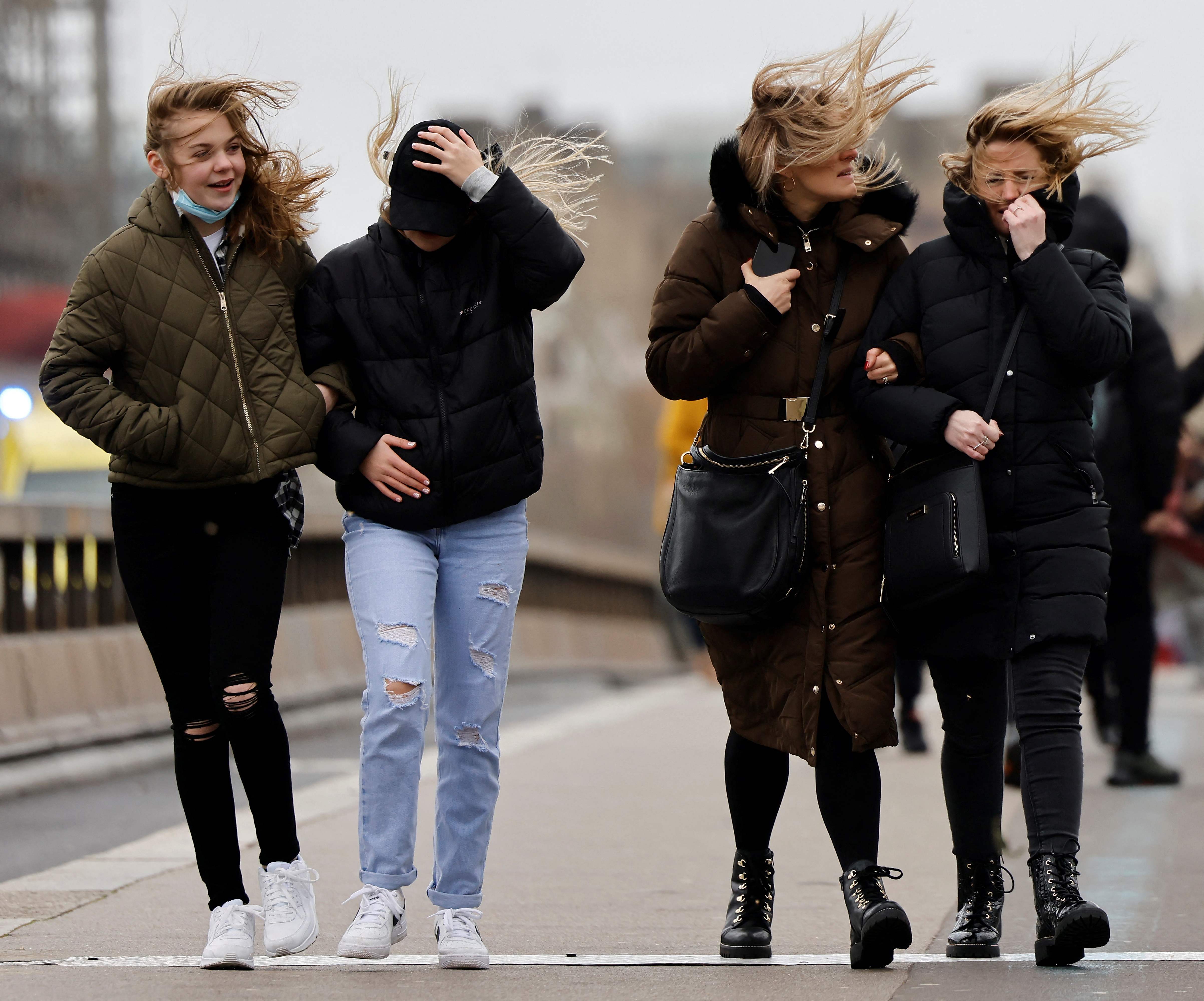 People struggle in the wind as they walk across Westminster Bridge, in central London