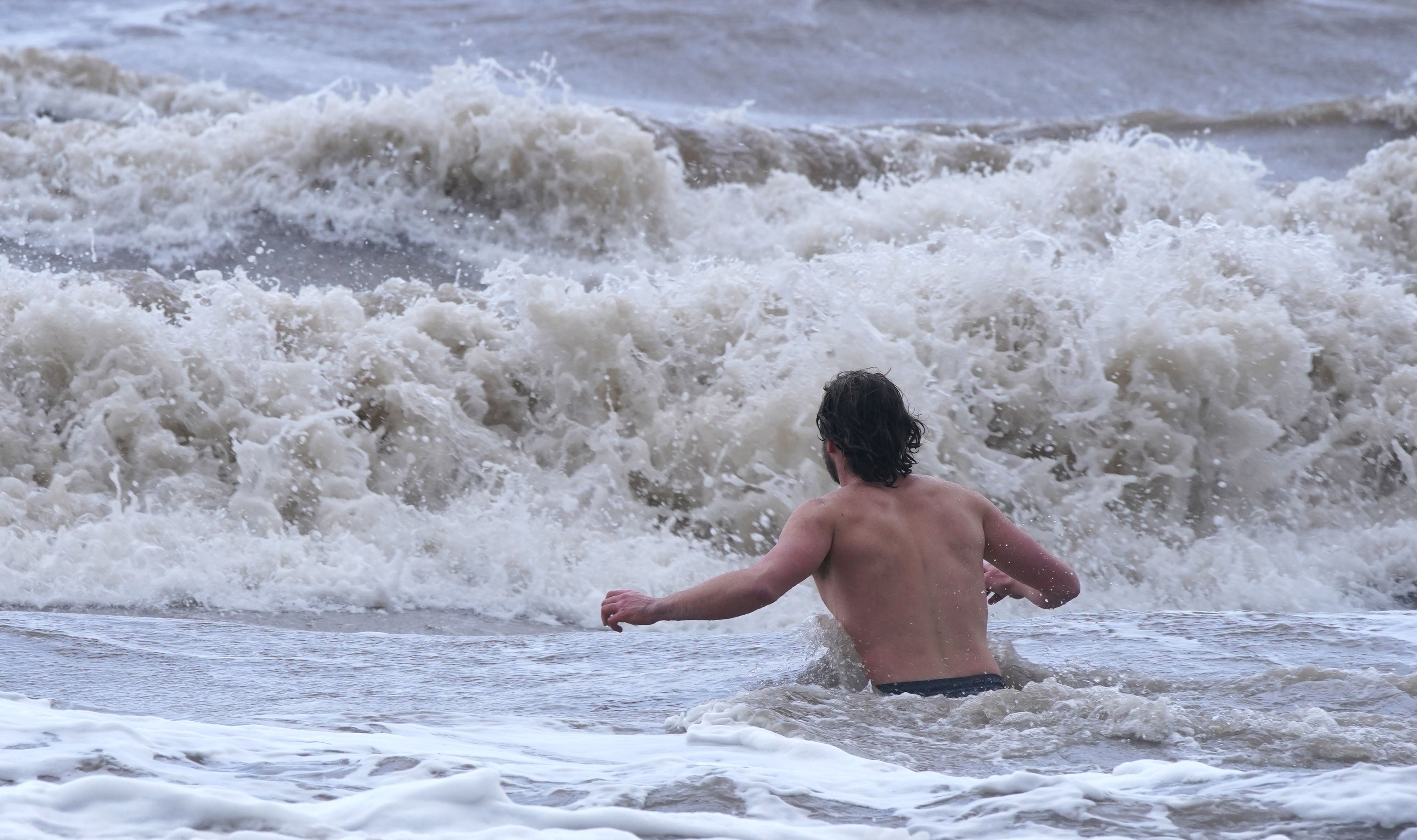 A man swims in the sea in New Brighton, Merseyside, as Storm Eunice hits the UK (Peter Byrne/PA)