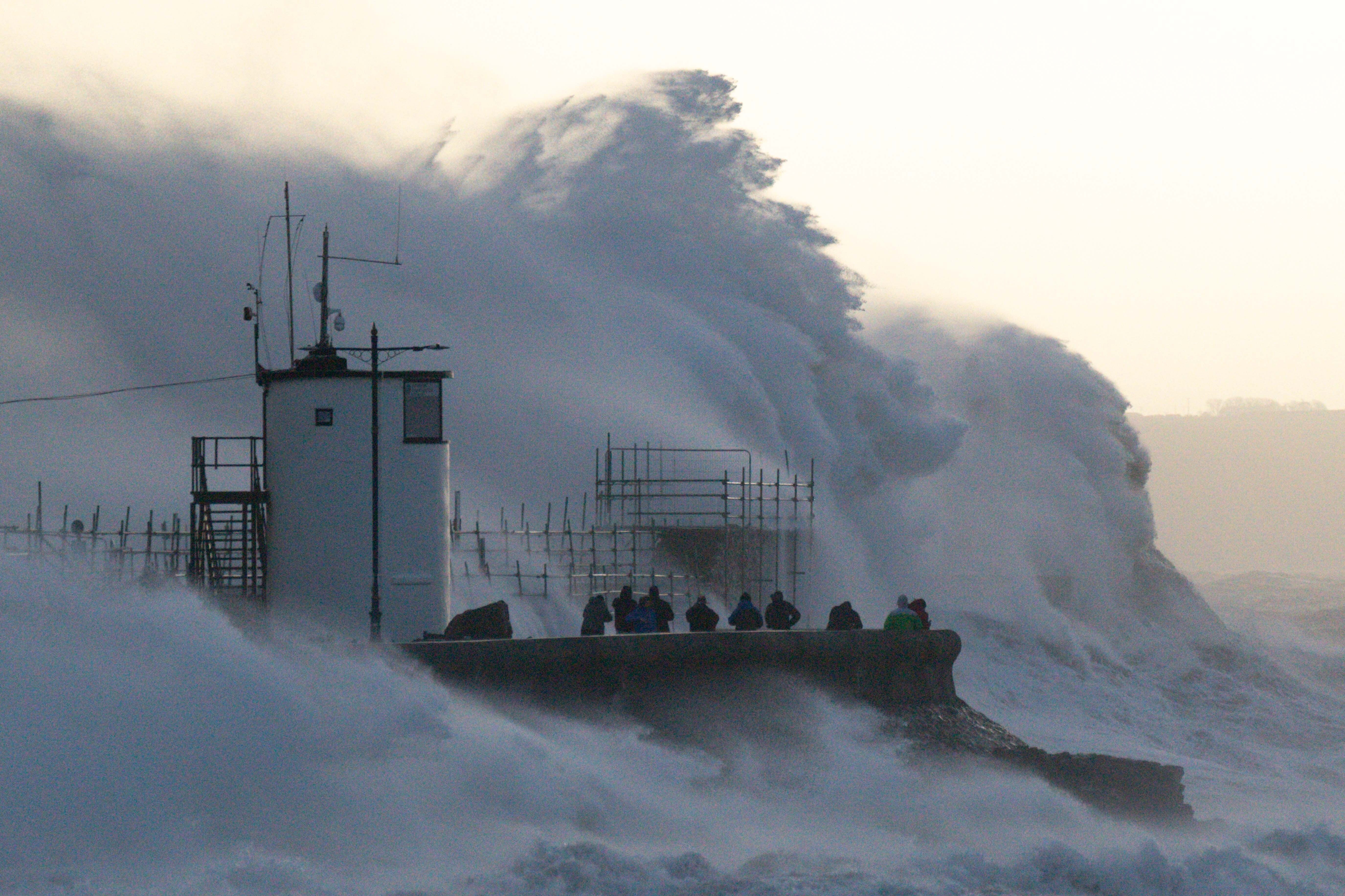 Waves crash against the sea wall and Porthcawl Lighthouse in Bridgend, Wales, during Storm Eunice