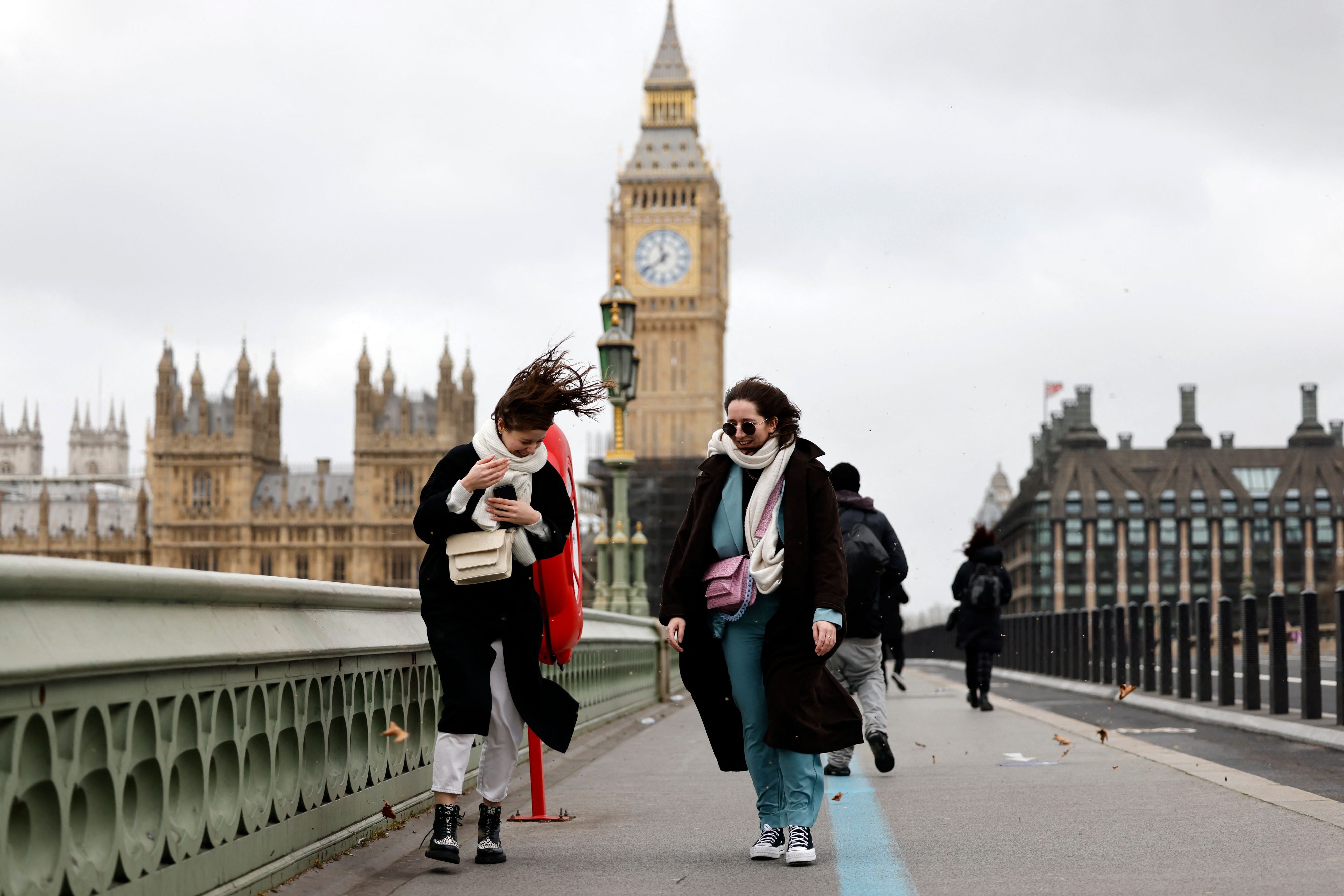People struggle in the wind as they walk across Westminster Bridge, near the Houses of Parliament in central London