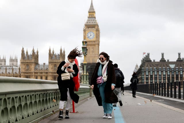 <p>People struggle in the wind as they walk across Westminster Bridge, near the Houses of Parliament in central London</p>