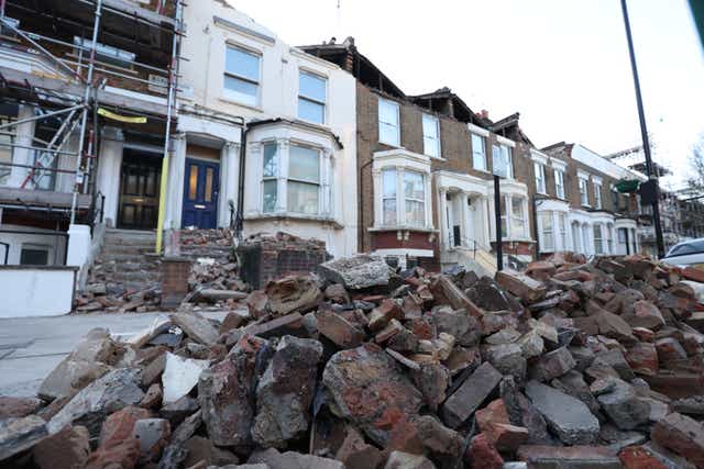 <p>A roadside filled with debris from the rooftops of three houses which were torn off during storm Eunice, on Kilburn Park Road in north west London</p>